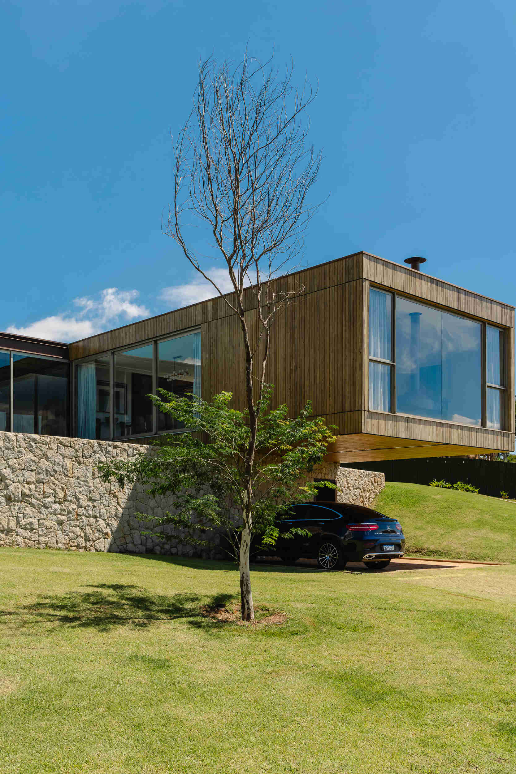 Casa Themis features a dramatic cantilevered living room suspended above a stone base, while integrated solar panels add sustainable performance to the sleek modern design.