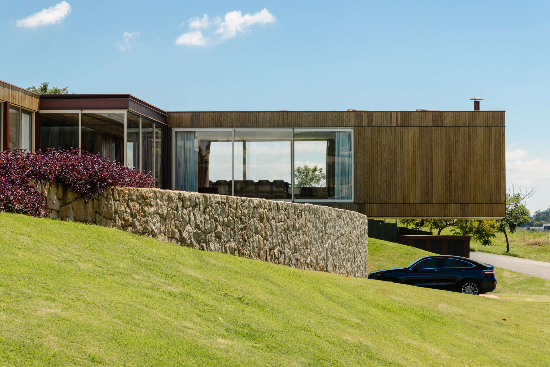 Casa Themis features a dramatic cantilevered living room suspended above a stone base, while integrated solar panels add sustainable performance to the sleek modern design.