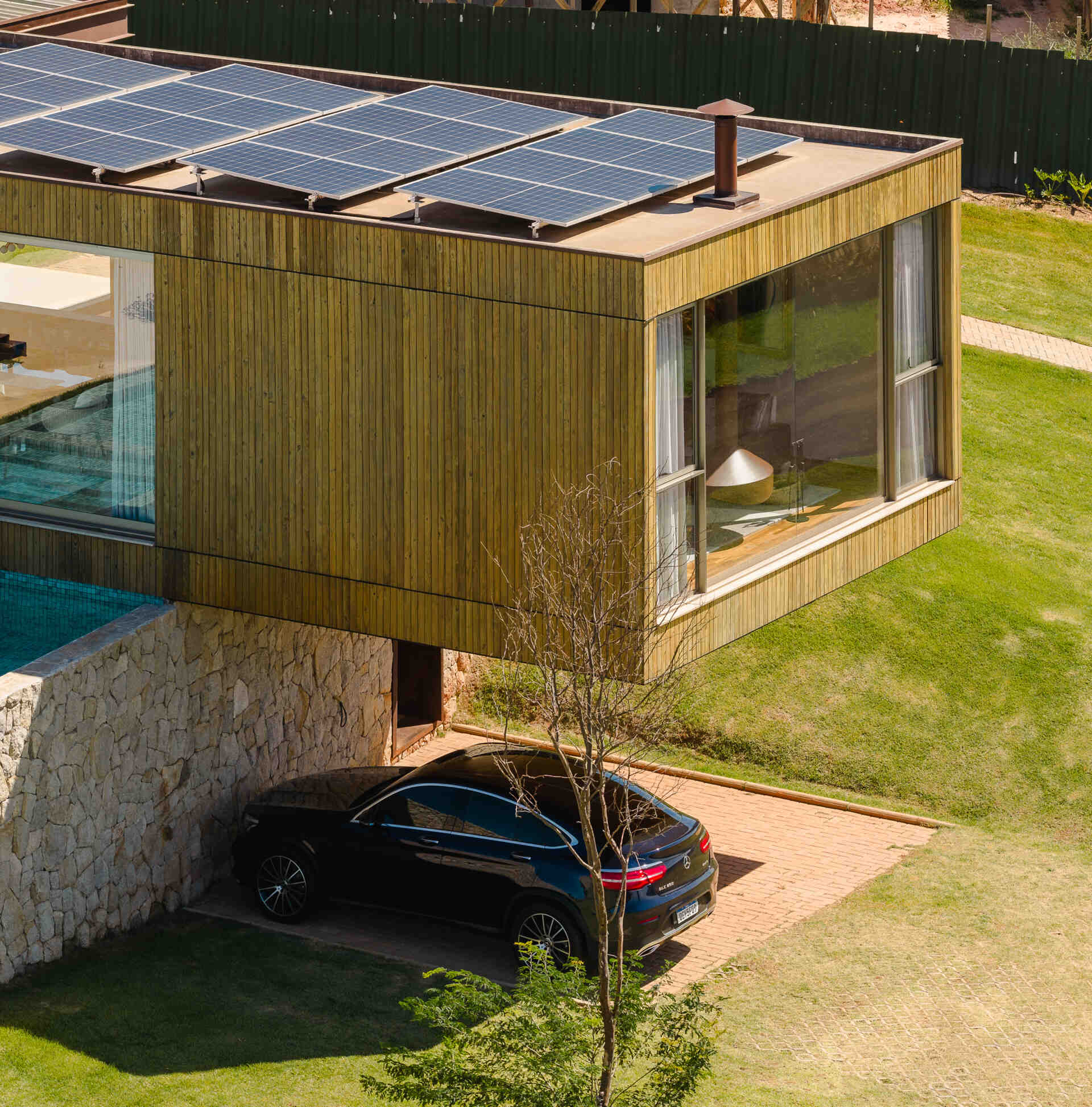 Casa Themis features a dramatic cantilevered living room suspended above a stone base, while integrated solar panels add sustainable performance to the sleek modern design.