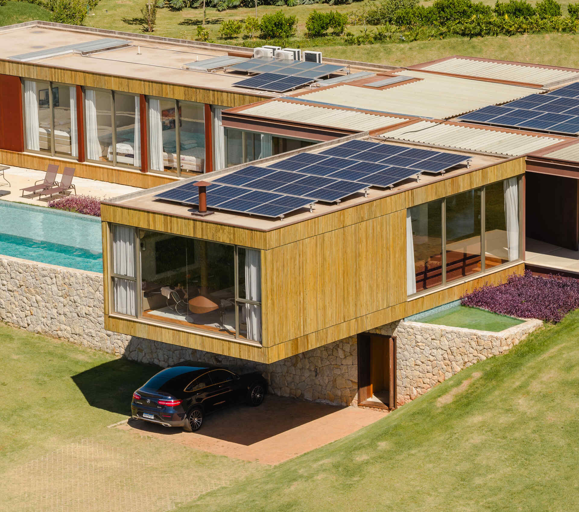 Casa Themis features a dramatic cantilevered living room suspended above a stone base, while integrated solar panels add sustainable performance to the sleek modern design.