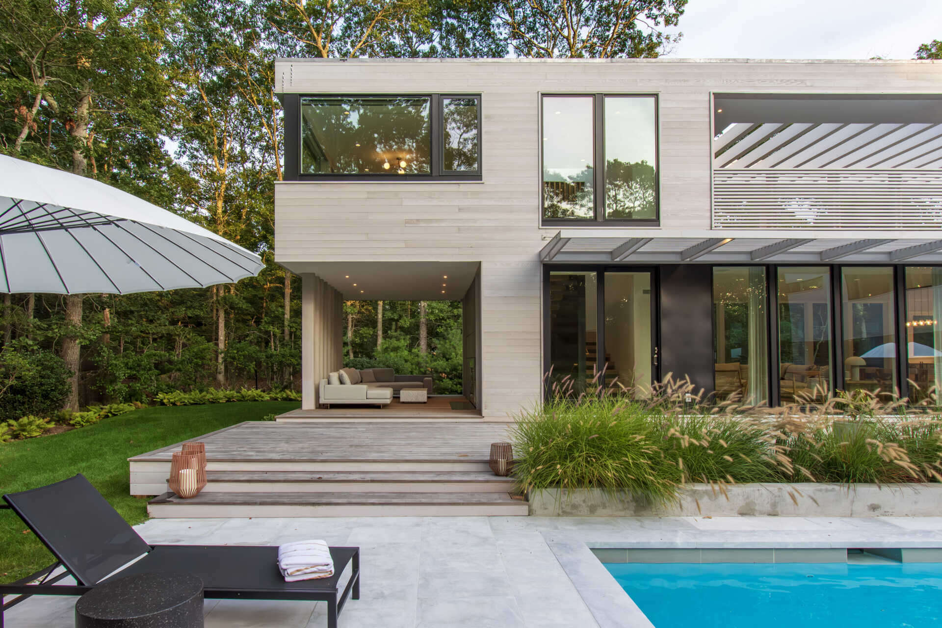 This modular East Hampton home combines bleached cedar siding, expansive glazing, and custom sun screens within a wooded setting.