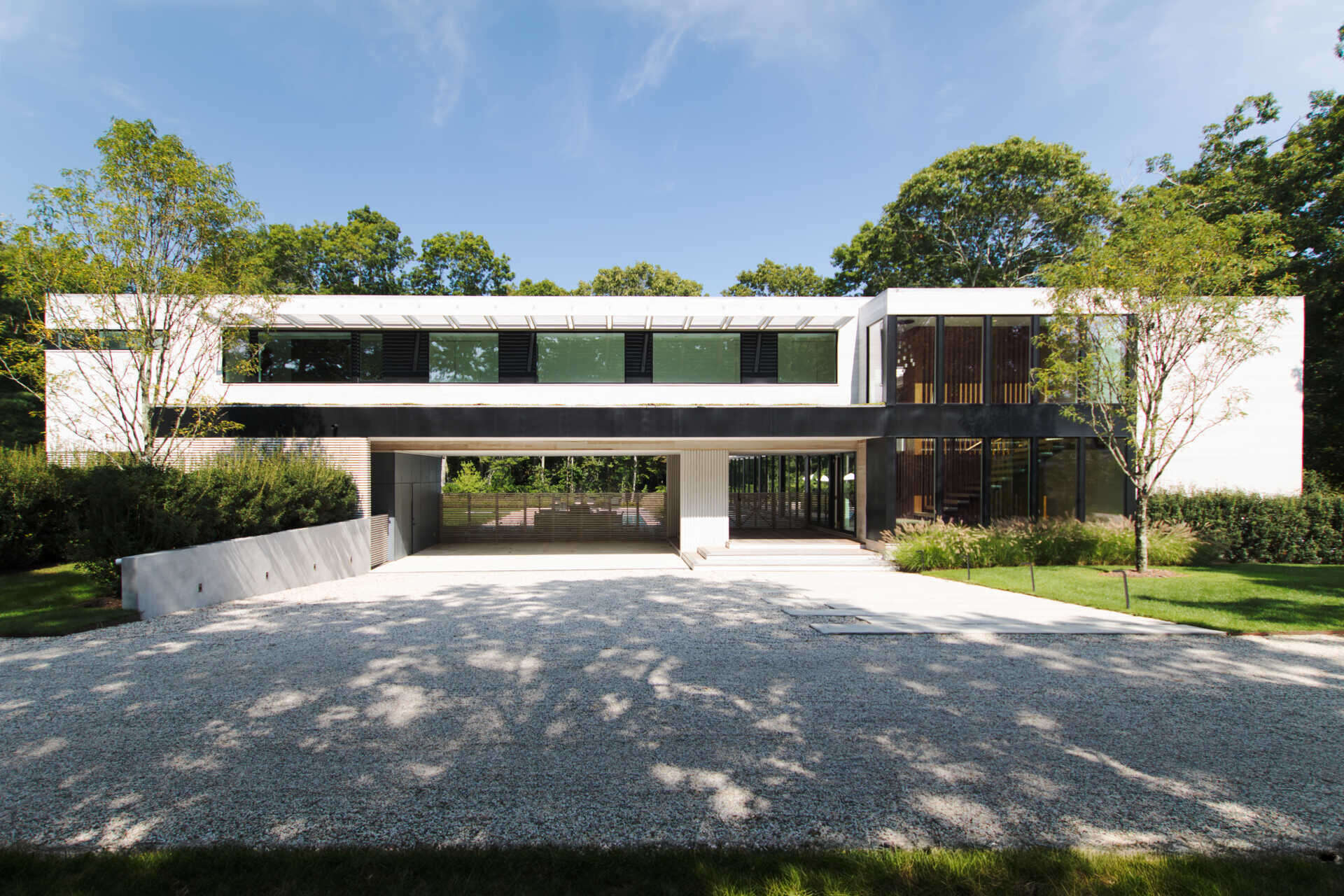 This modular East Hampton home combines bleached cedar siding, expansive glazing, and custom sun screens within a wooded setting.