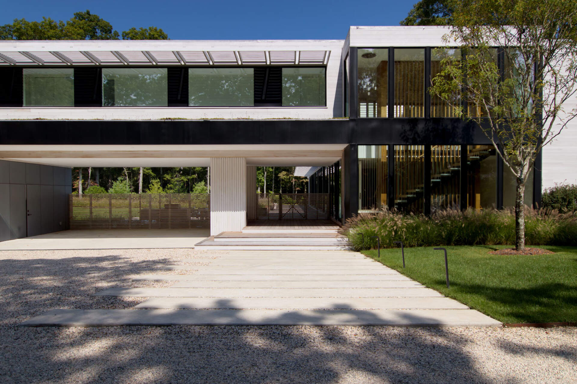This modular East Hampton home combines bleached cedar siding, expansive glazing, and custom sun screens within a wooded setting.