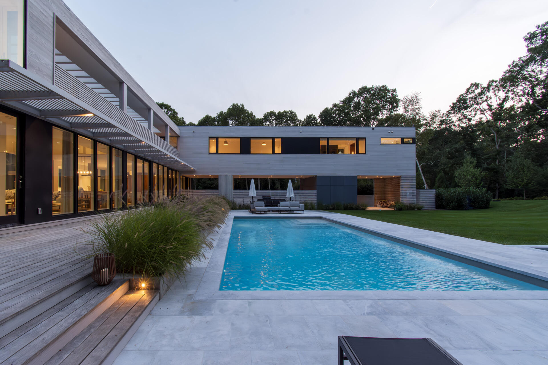This modular East Hampton home combines bleached cedar siding, expansive glazing, and custom sun screens within a wooded setting.