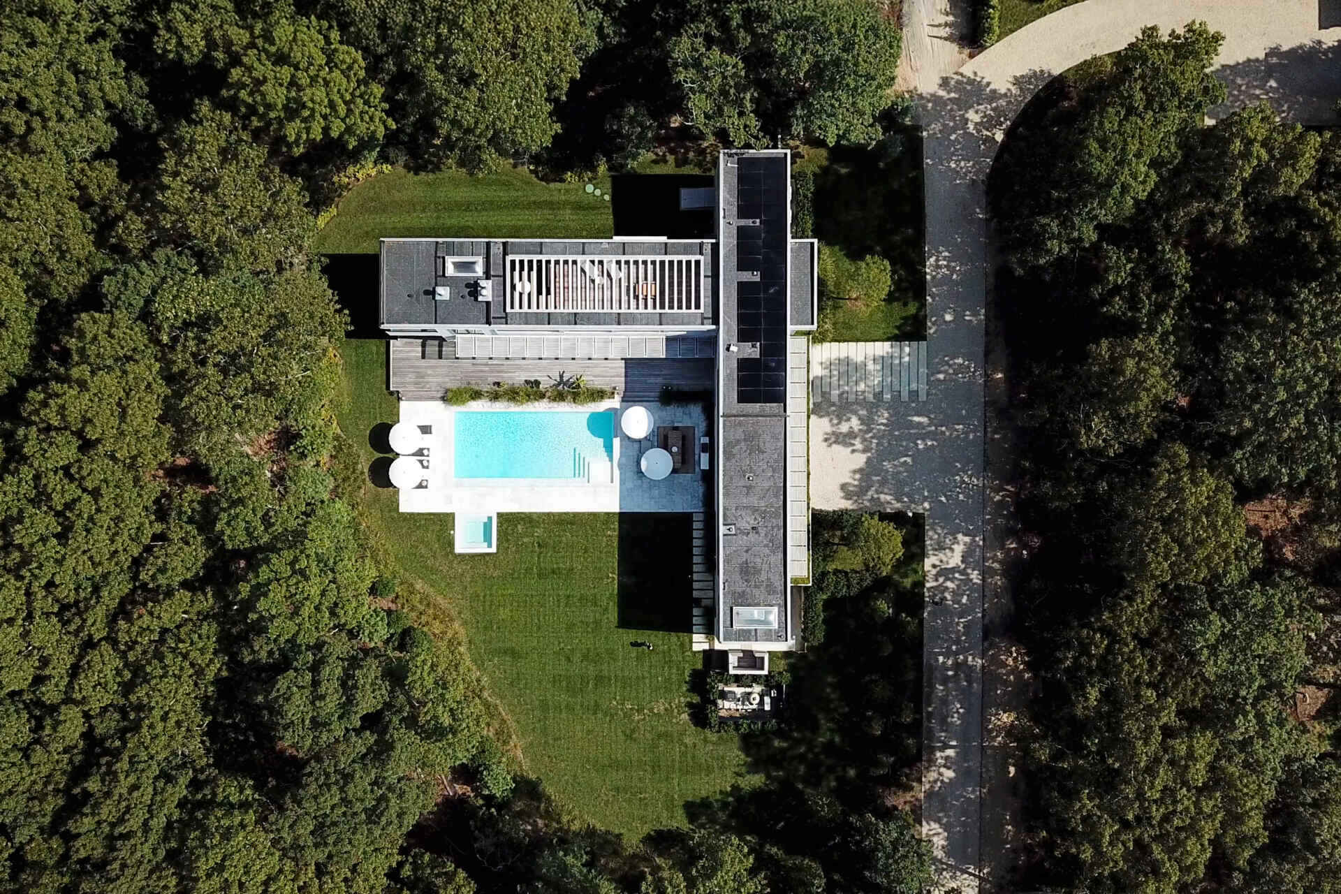 This modular East Hampton home combines bleached cedar siding, expansive glazing, and custom sun screens within a wooded setting.