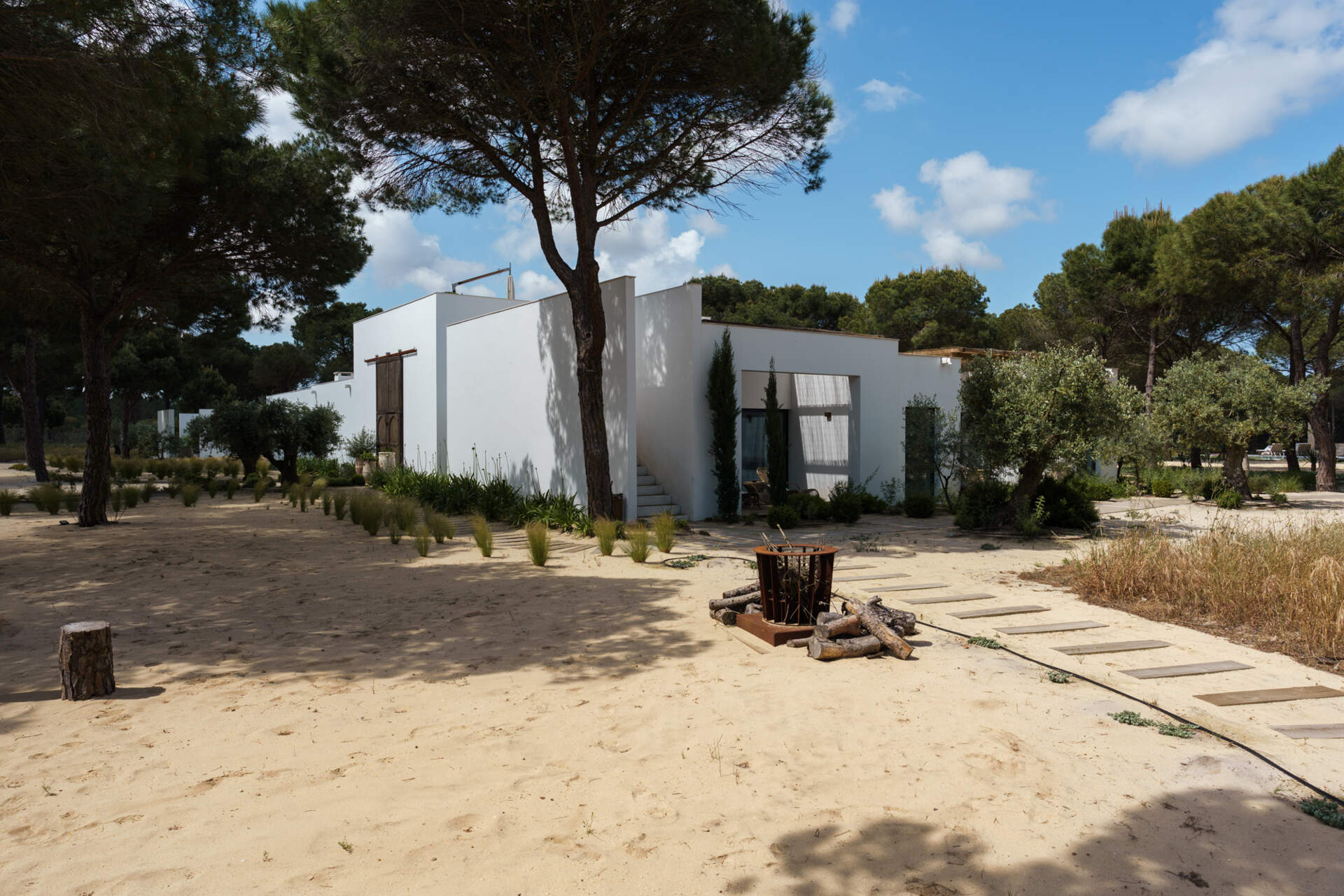 This L-shaped villa in Comporta uses white walls, timber screens, and retractable glass doors to create a modern home filled with light, shadow, and forest views.