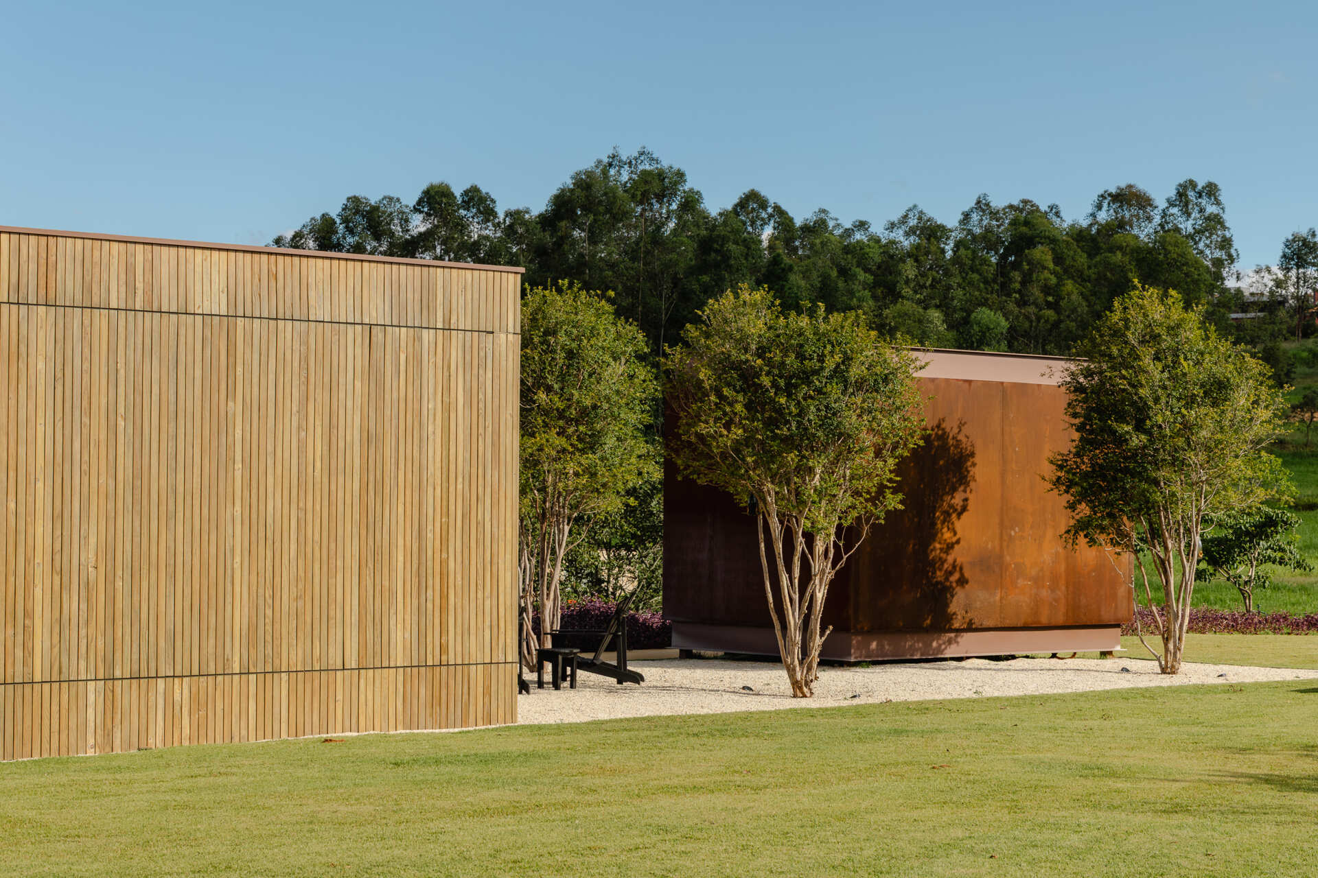 Stone walls, vertical timber slats, and lightweight steel construction give Casa Themis a warm contemporary look while helping the home blend naturally into the Brazilian landscape.