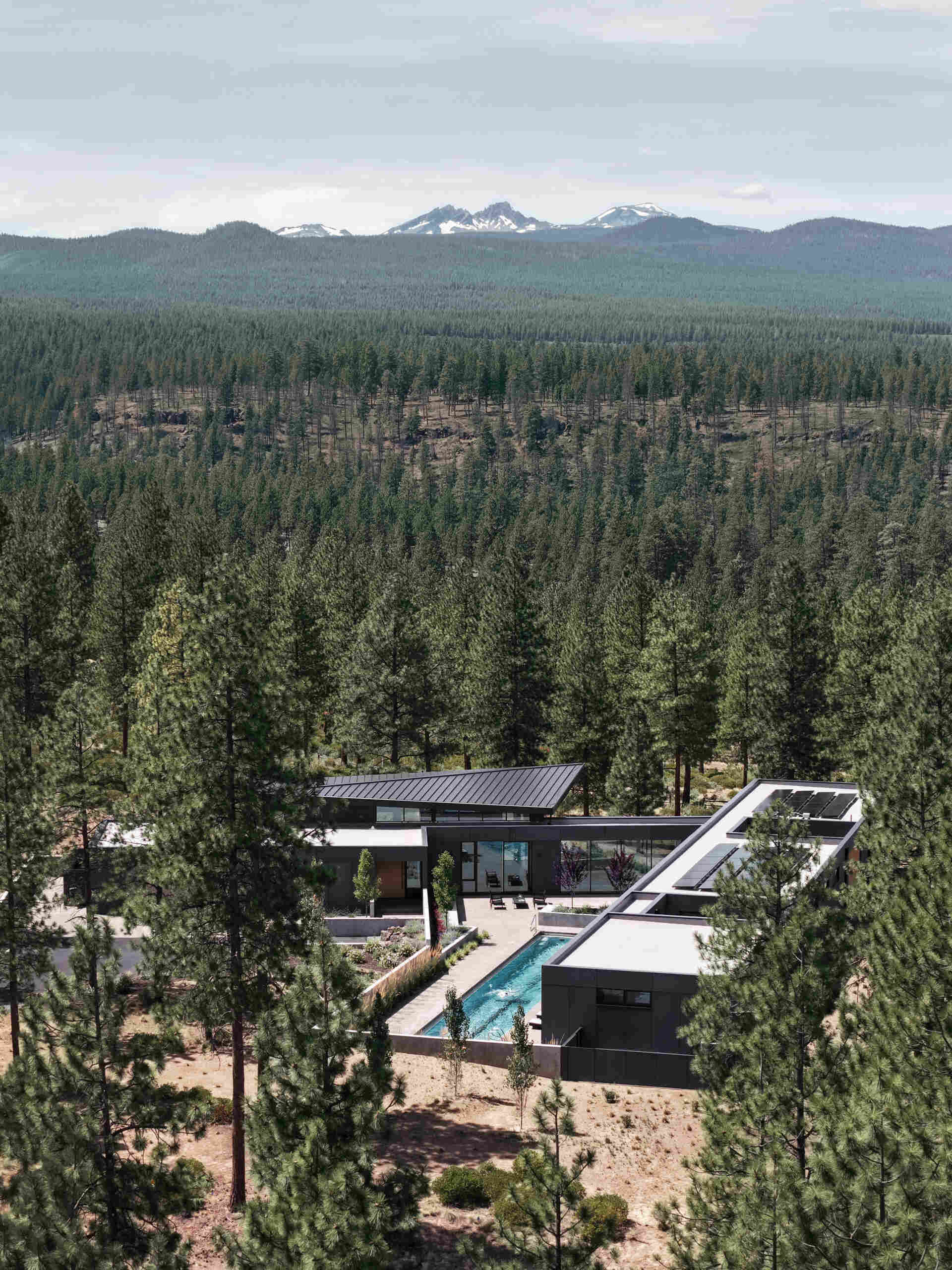 This modern Oregon home combines concrete, black steel, warm wood, and dramatic rooflines for a bold exterior that feels perfectly suited to the forest landscape.