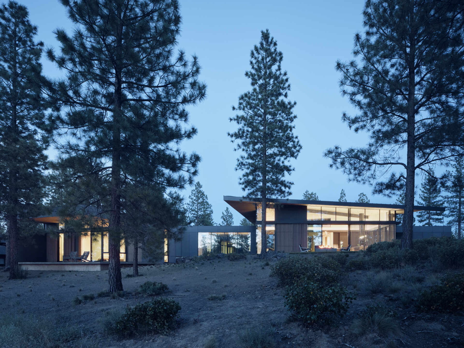 This modern Oregon home combines concrete, black steel, warm wood, and dramatic rooflines for a bold exterior that feels perfectly suited to the forest landscape.