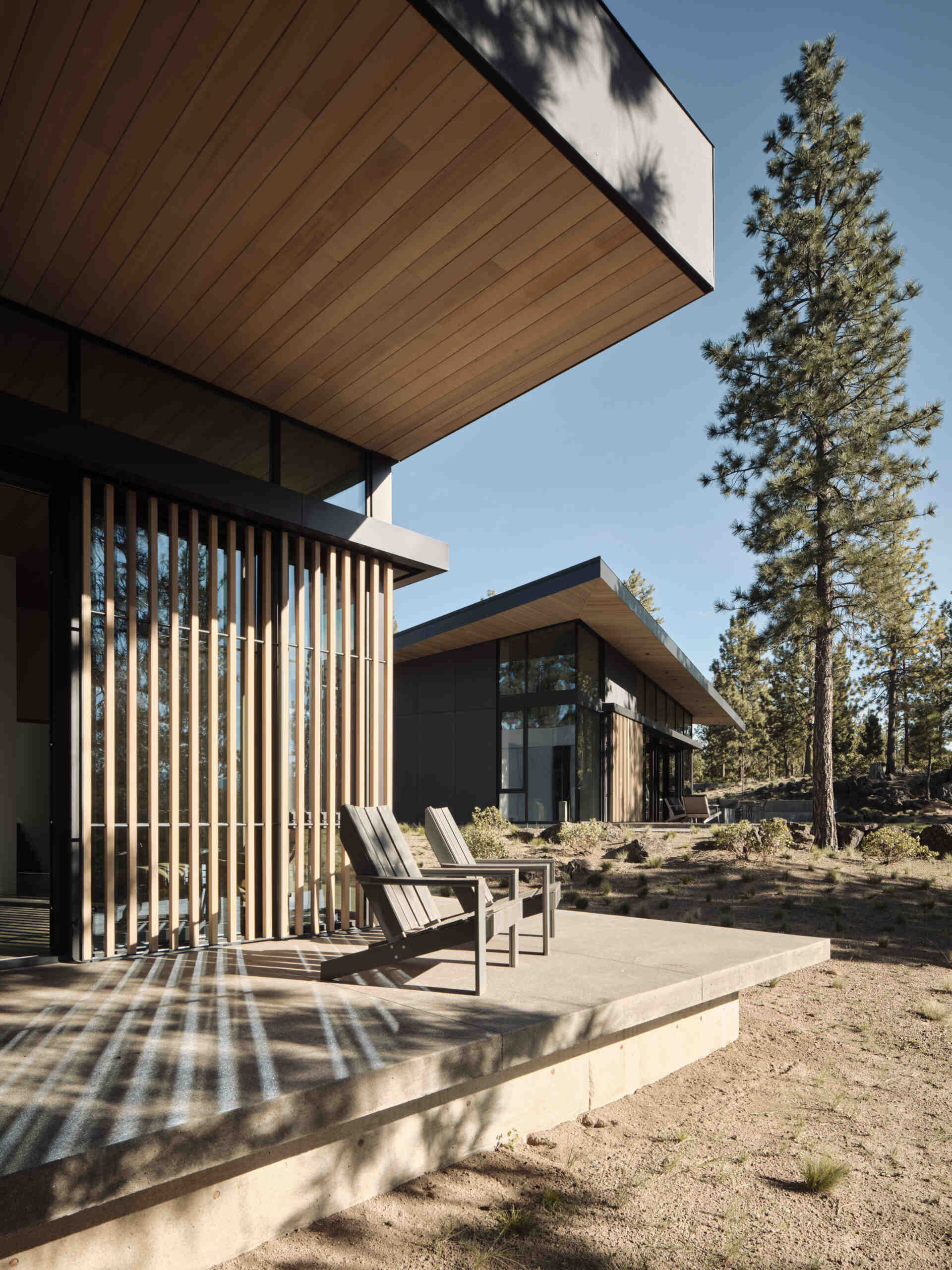 This modern Oregon home combines concrete, black steel, warm wood, and dramatic rooflines for a bold exterior that feels perfectly suited to the forest landscape.