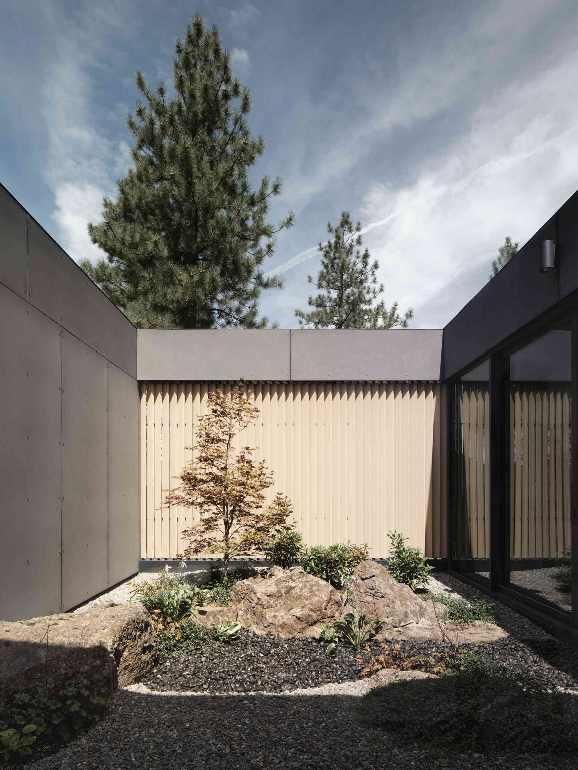 This modern Oregon home combines concrete, black steel, warm wood, and dramatic rooflines for a bold exterior that feels perfectly suited to the forest landscape.