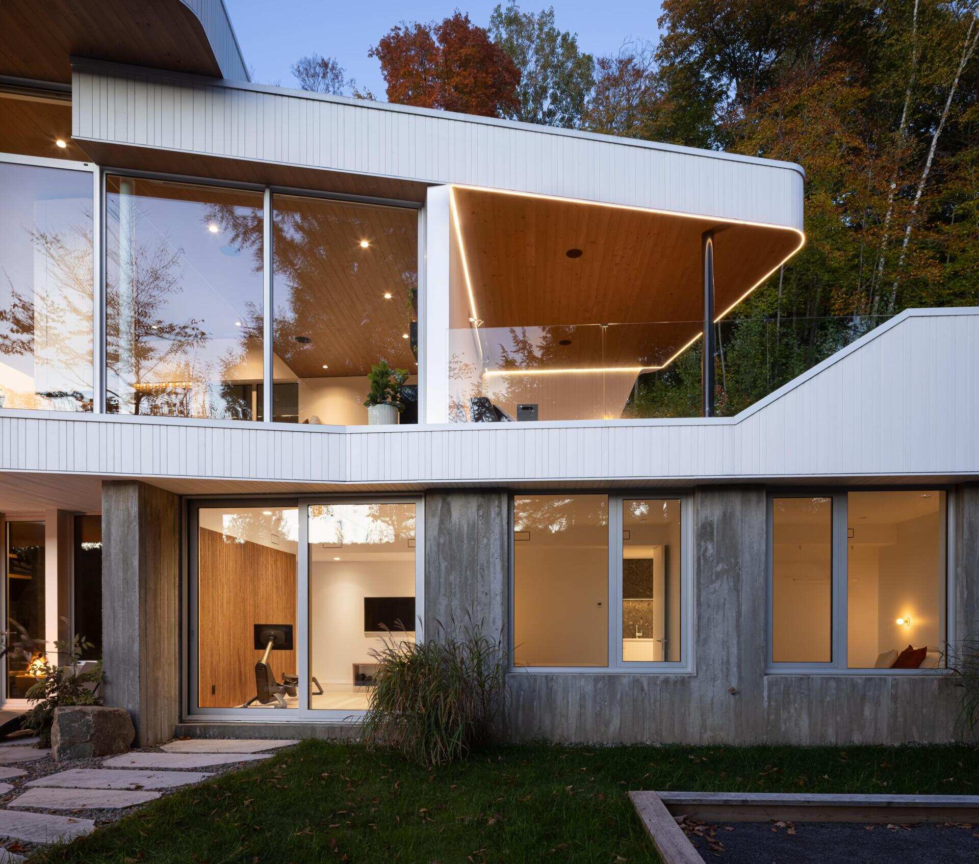 Layered white volumes, dramatic cantilevers, and retro-futuristic forms give this Québec mountain home a striking architectural identity above Lake Xavier.