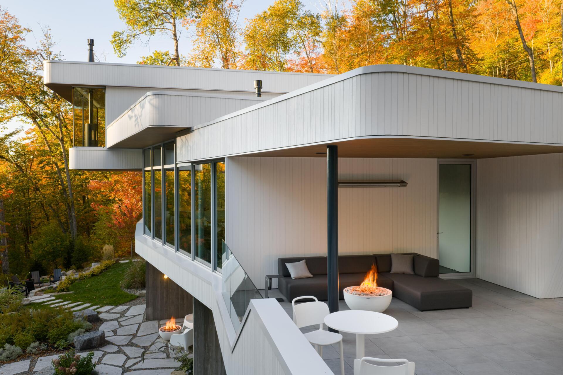 Layered white volumes, dramatic cantilevers, and retro-futuristic forms give this Québec mountain home a striking architectural identity above Lake Xavier.