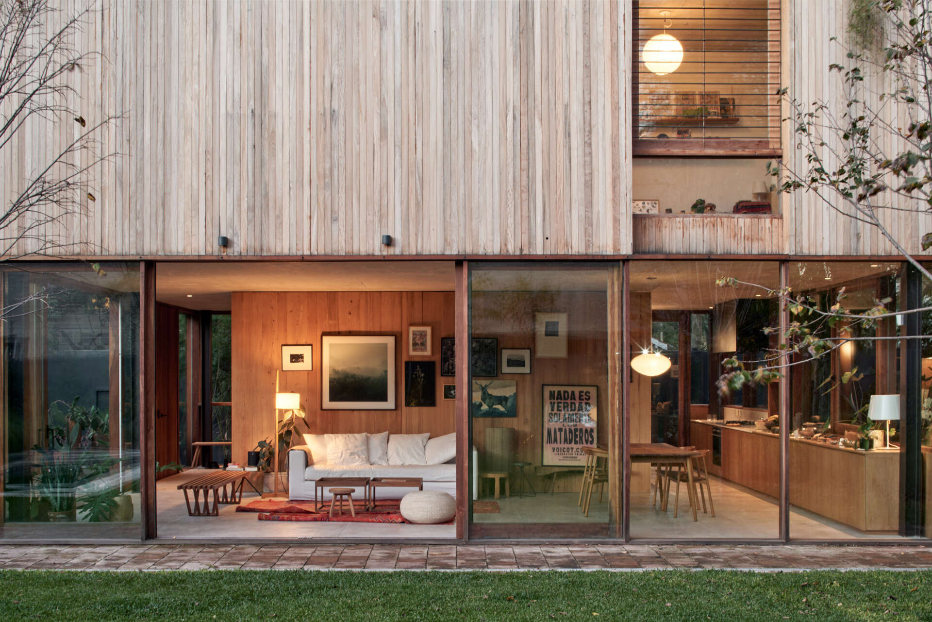 Glass walls below and vertical wood above create a layered facade, with a metal frame designed to support climbing greenery.