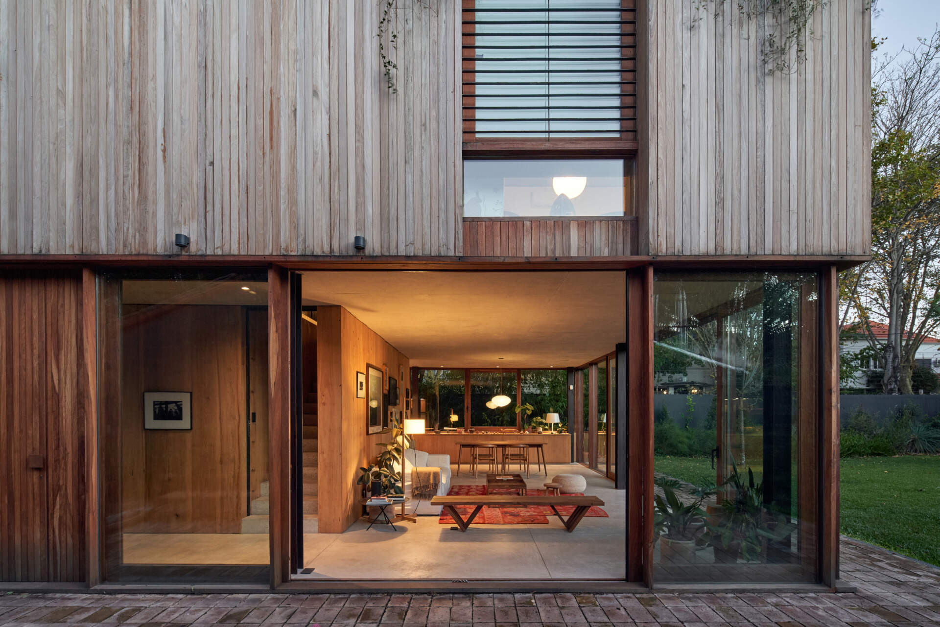 An open living and dining area flows straight into a brick patio, with sliding glass doors creating a seamless indoor-outdoor space.
