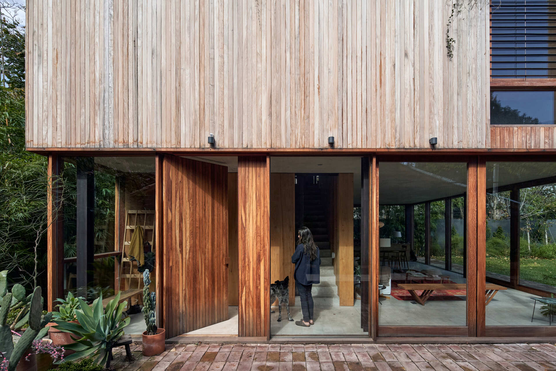 A full-height wood front door adds warmth and scale, creating a welcoming entry behind the brick facade.