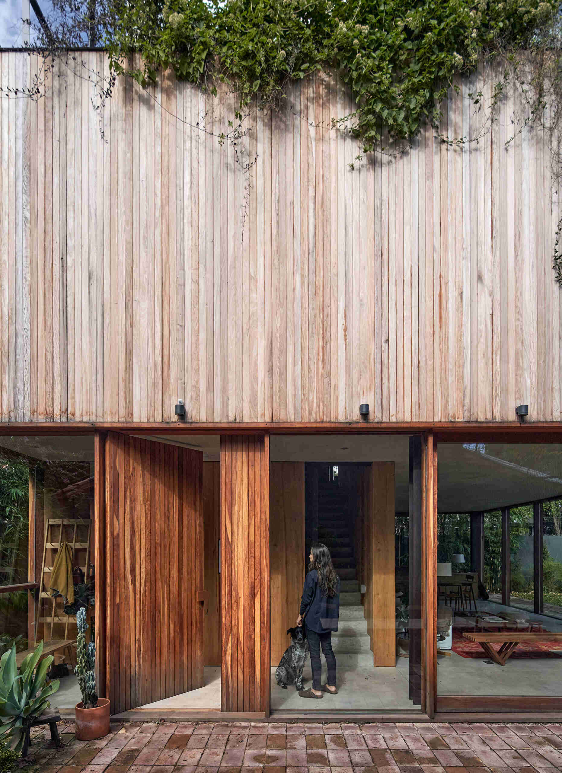 A full-height wood front door adds warmth and scale, creating a welcoming entry behind the brick facade.