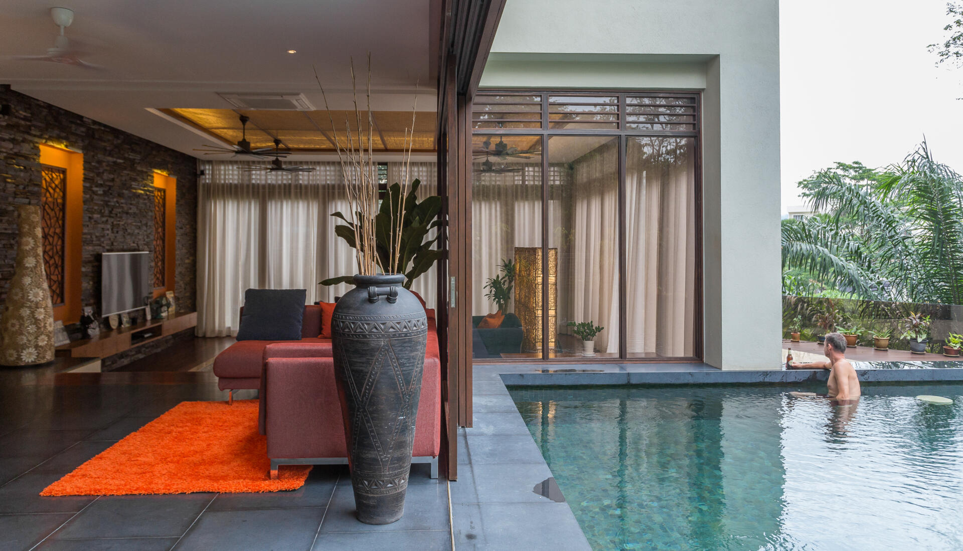 This tropical hillside pool in Kuala Lumpur is surrounded by dense greenery, shaded outdoor spaces and a floating timber canopy that blends into the jungle landscape.
