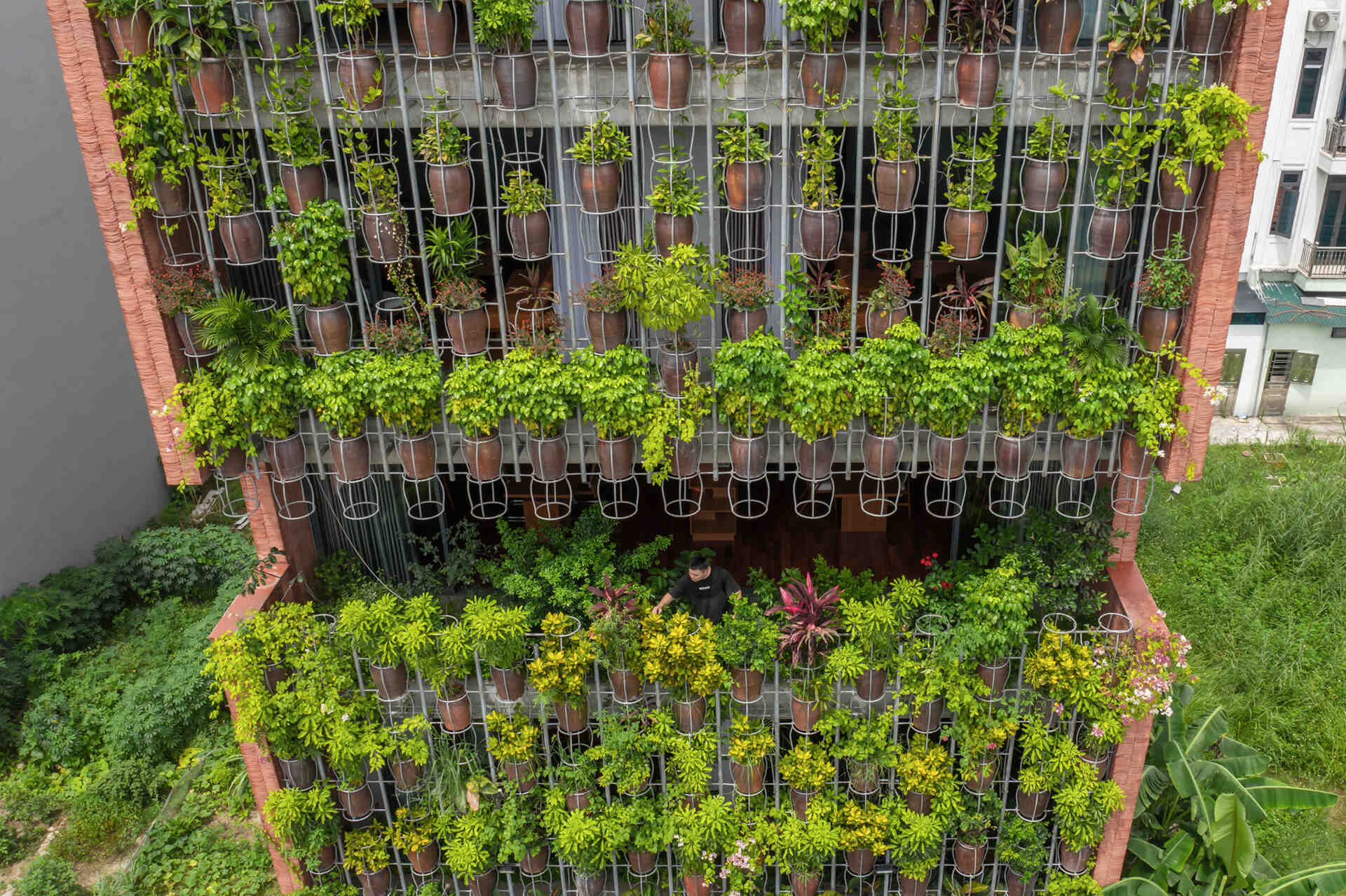 A facade made of hanging ceramic pots creates a vertical garden that filters light, air, and views.
