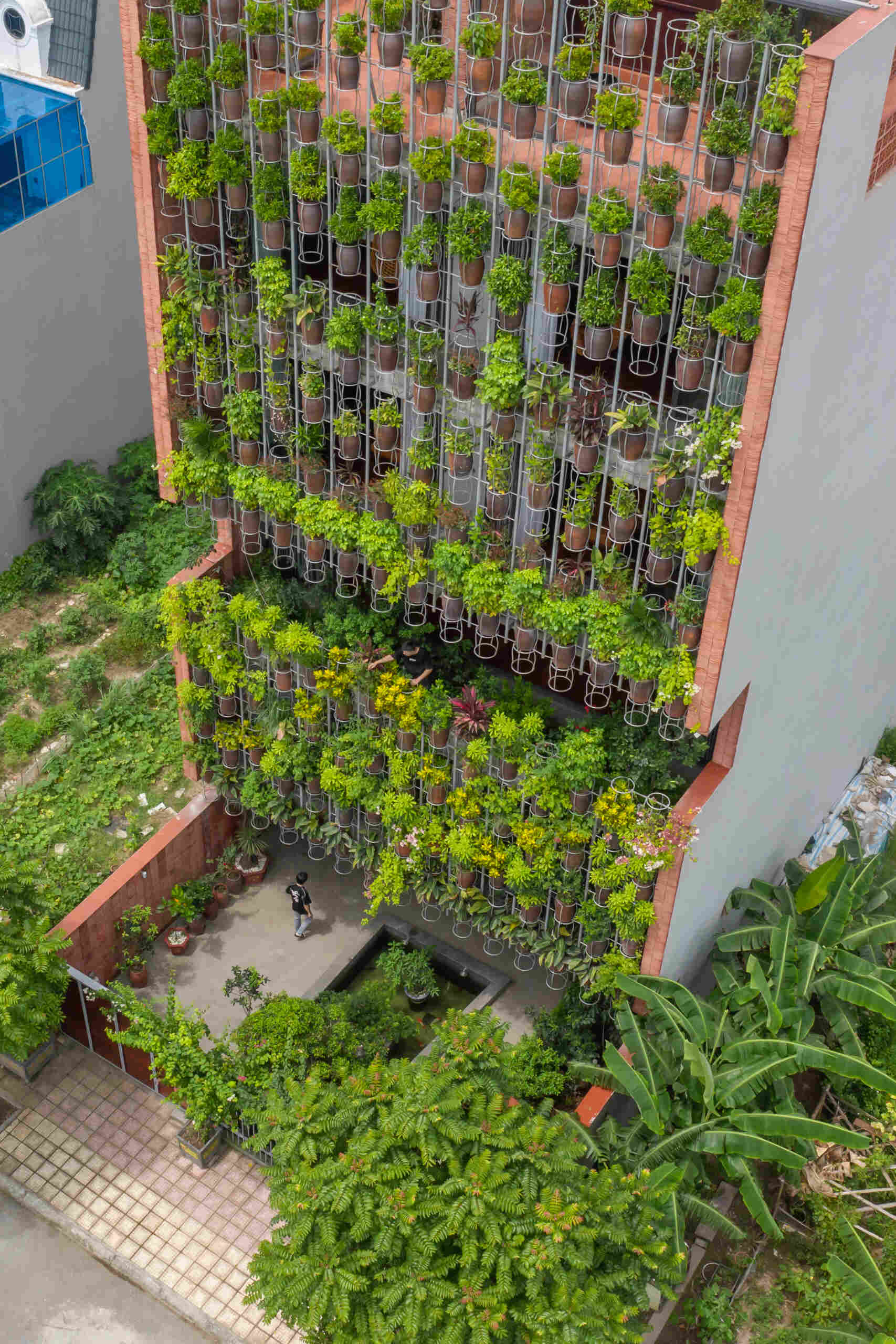A facade made of hanging ceramic pots creates a vertical garden that filters light, air, and views.