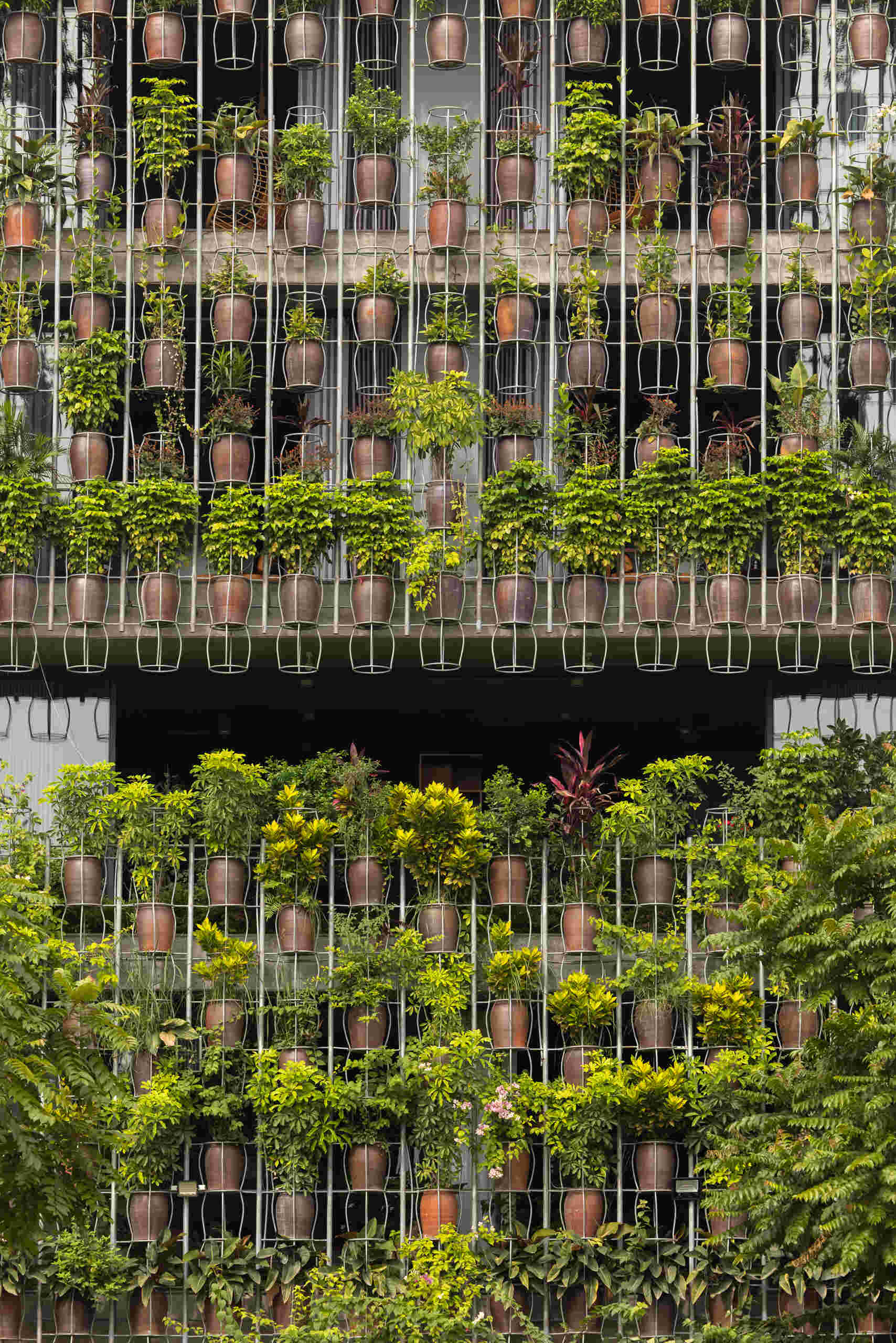 A facade made of hanging ceramic pots creates a vertical garden that filters light, air, and views.