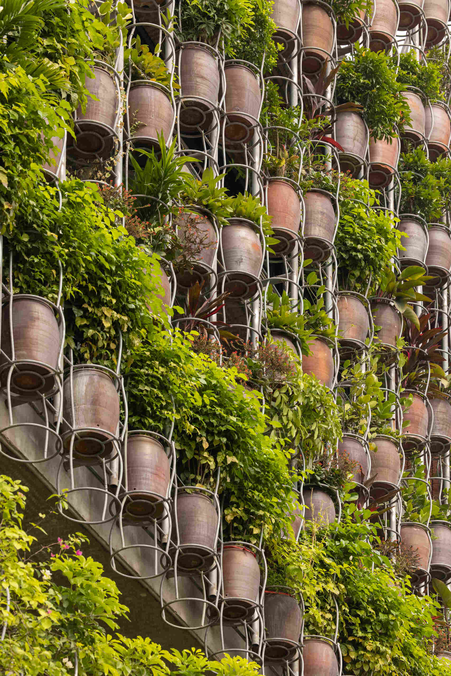 A facade made of hanging ceramic pots creates a vertical garden that filters light, air, and views.