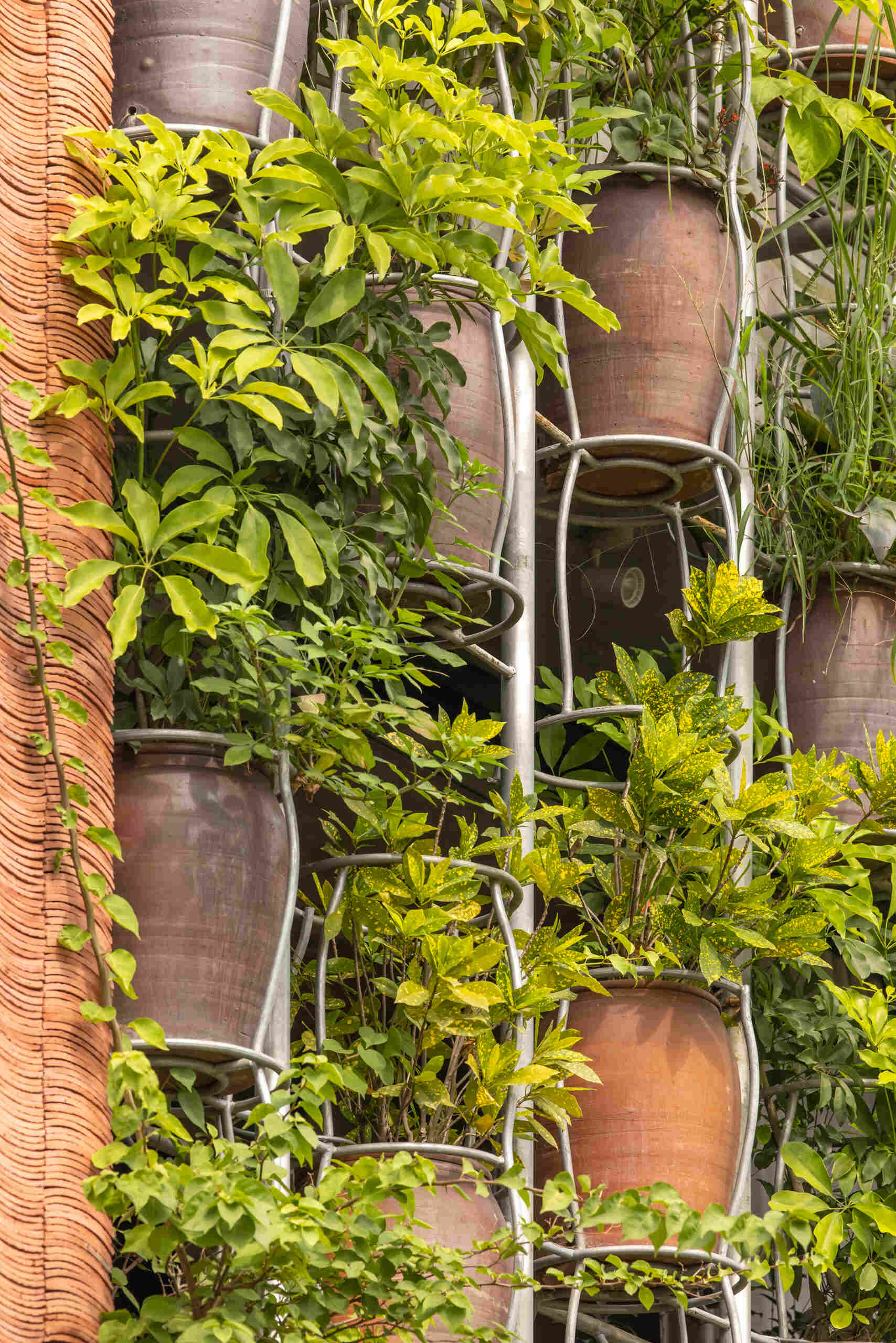 A facade made of hanging ceramic pots creates a vertical garden that filters light, air, and views.