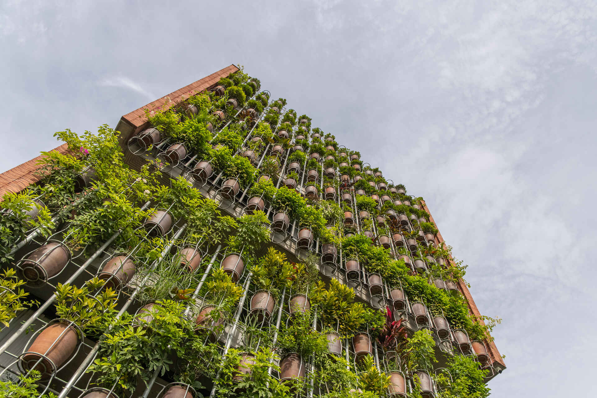 A facade made of hanging ceramic pots creates a vertical garden that filters light, air, and views.