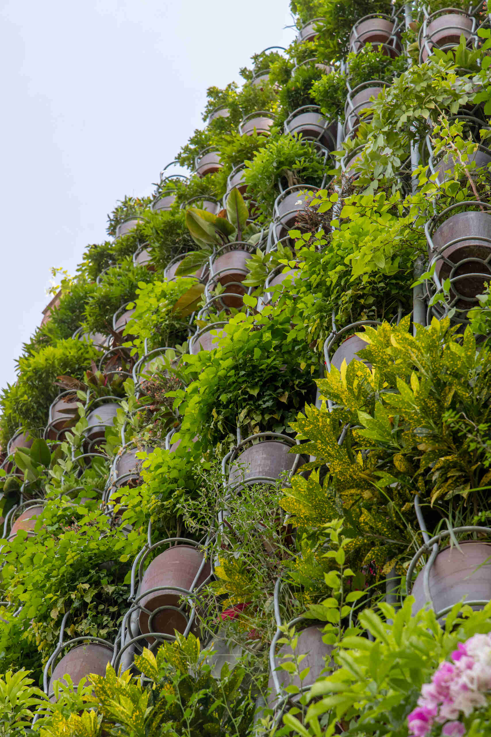 A facade made of hanging ceramic pots creates a vertical garden that filters light, air, and views.