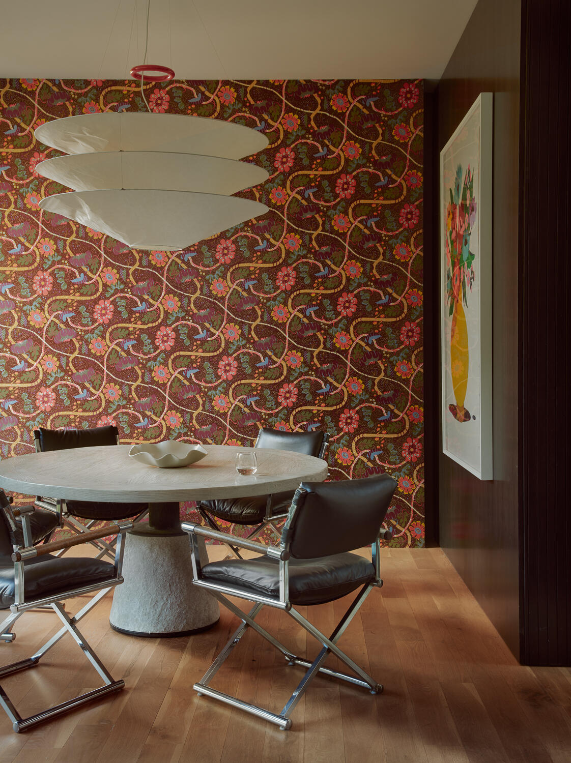 Bold floral wallcovering, sculptural lighting, rich wood finishes, and contemporary furnishings give the dining room a distinctive personality while adding warmth and character to the home's modern interior.