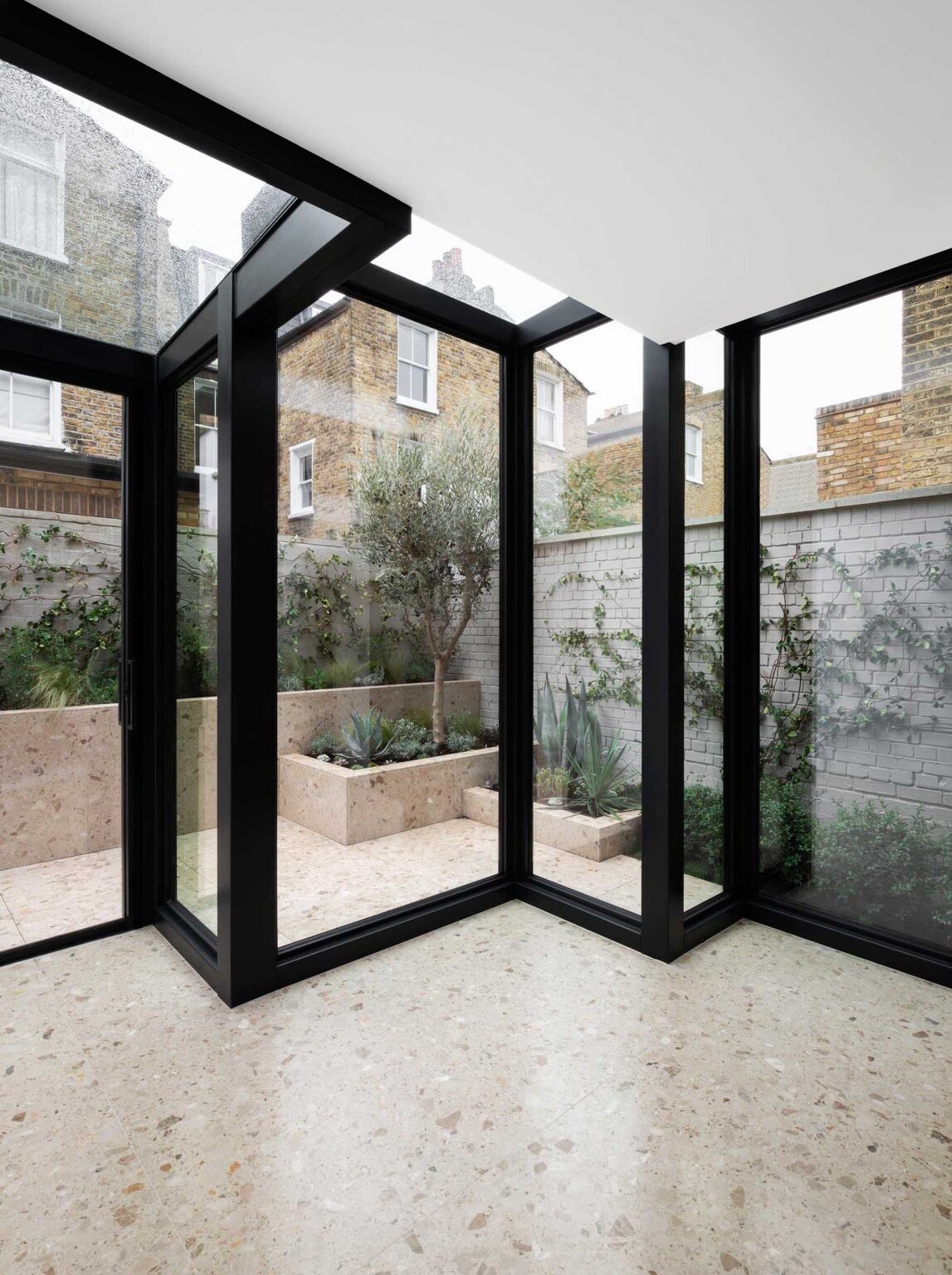 A Victorian terraced house in London transformed with cubist glass volumes, black steel framing, and dramatic geometric forms by Bureau de Change Architects.