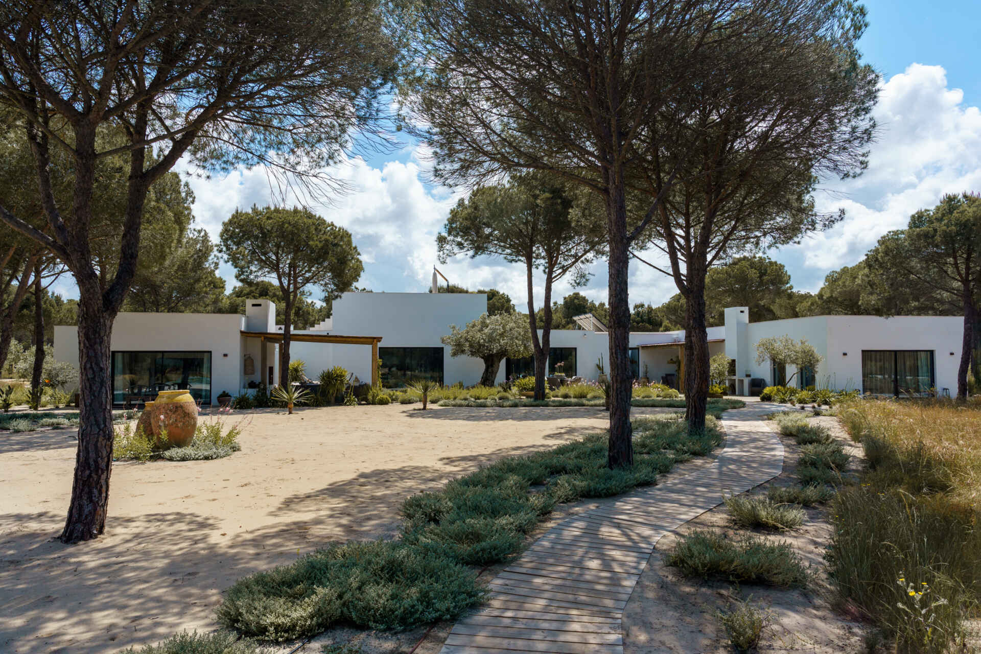 Native dune plants, cork oaks, limestone pathways, and Mediterranean greenery give this Comporta villa a natural landscape that feels effortlessly integrated with the architecture.
