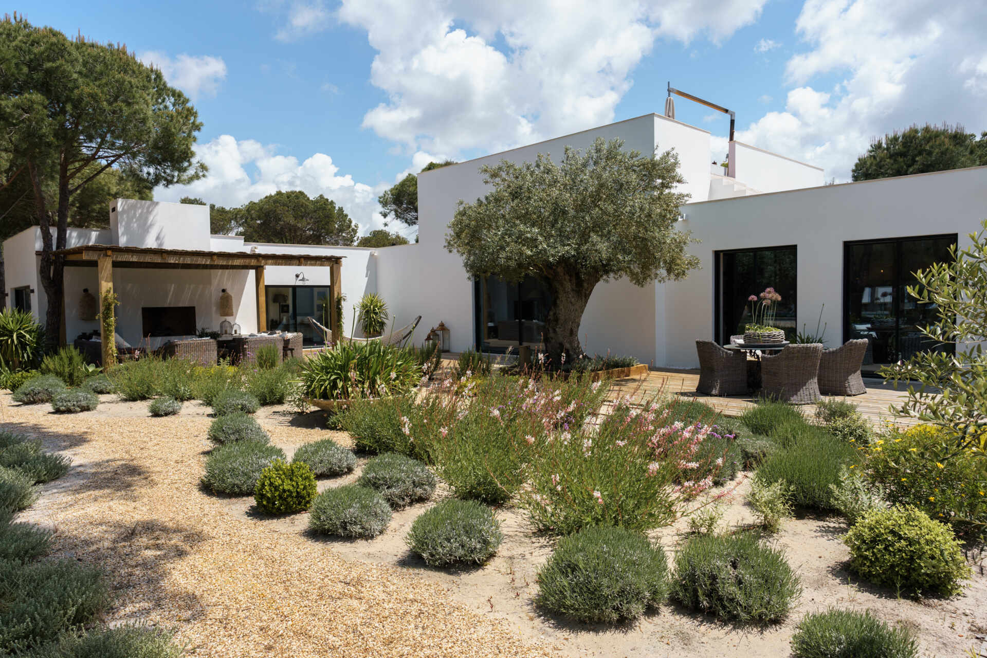 Native dune plants, cork oaks, limestone pathways, and Mediterranean greenery give this Comporta villa a natural landscape that feels effortlessly integrated with the architecture.