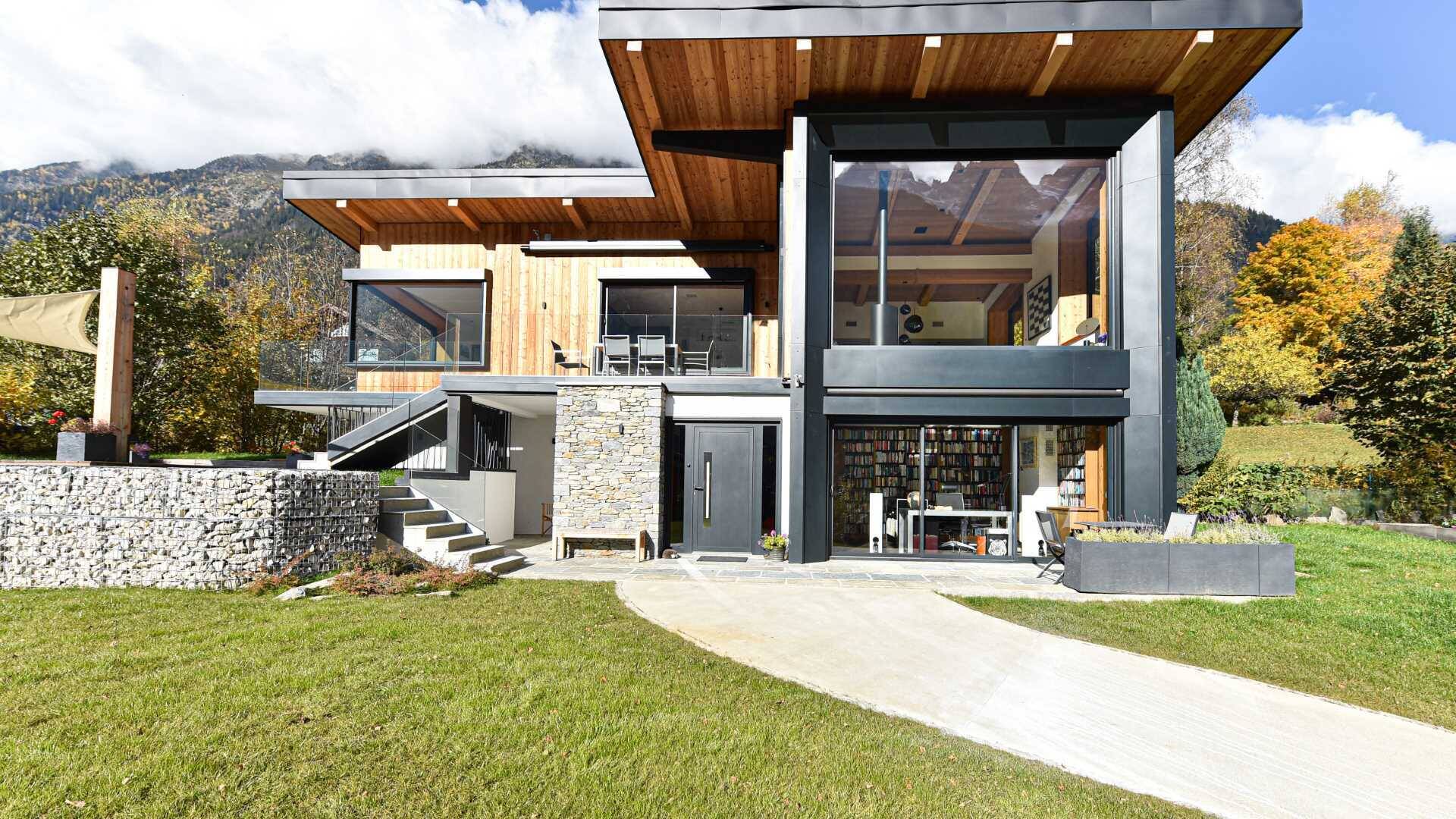 This Chamonix renovation features a massive black framed picture window that perfectly captures mountain views while flooding the home with natural light.