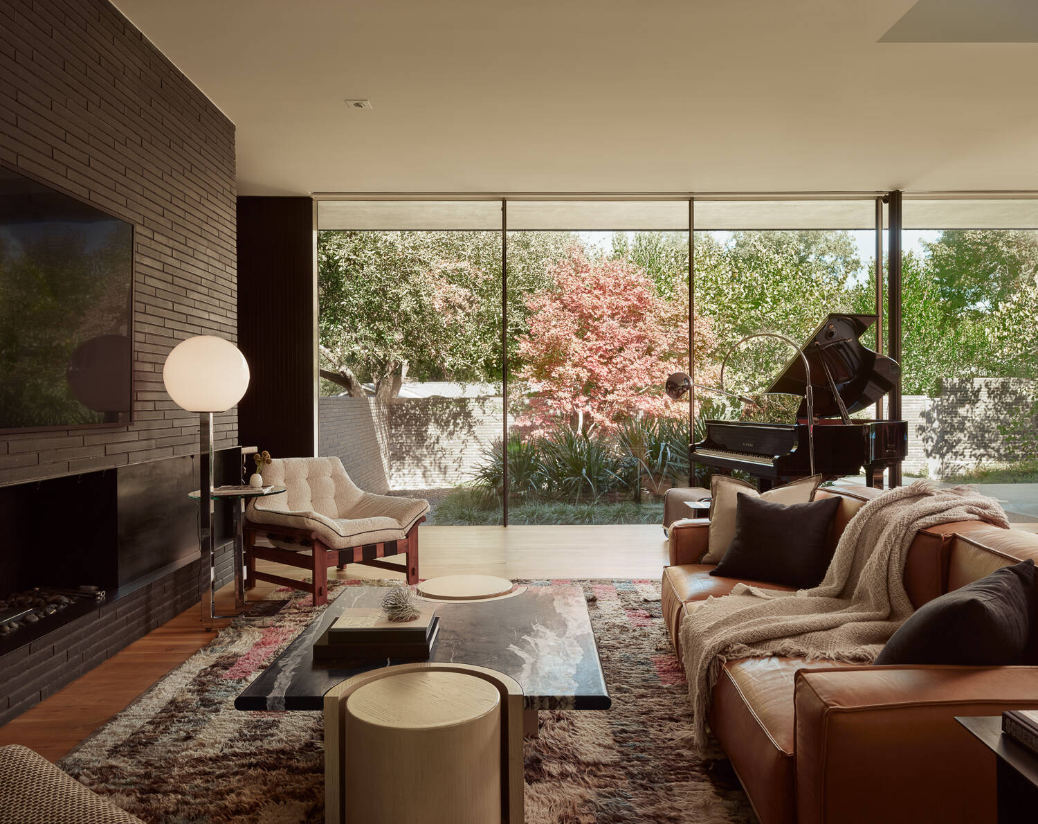Explore a light-filled living room centered around courtyard views, floor-to-ceiling glazing, and a dramatic overhead monitor that draws natural light deep into the heart of the home.