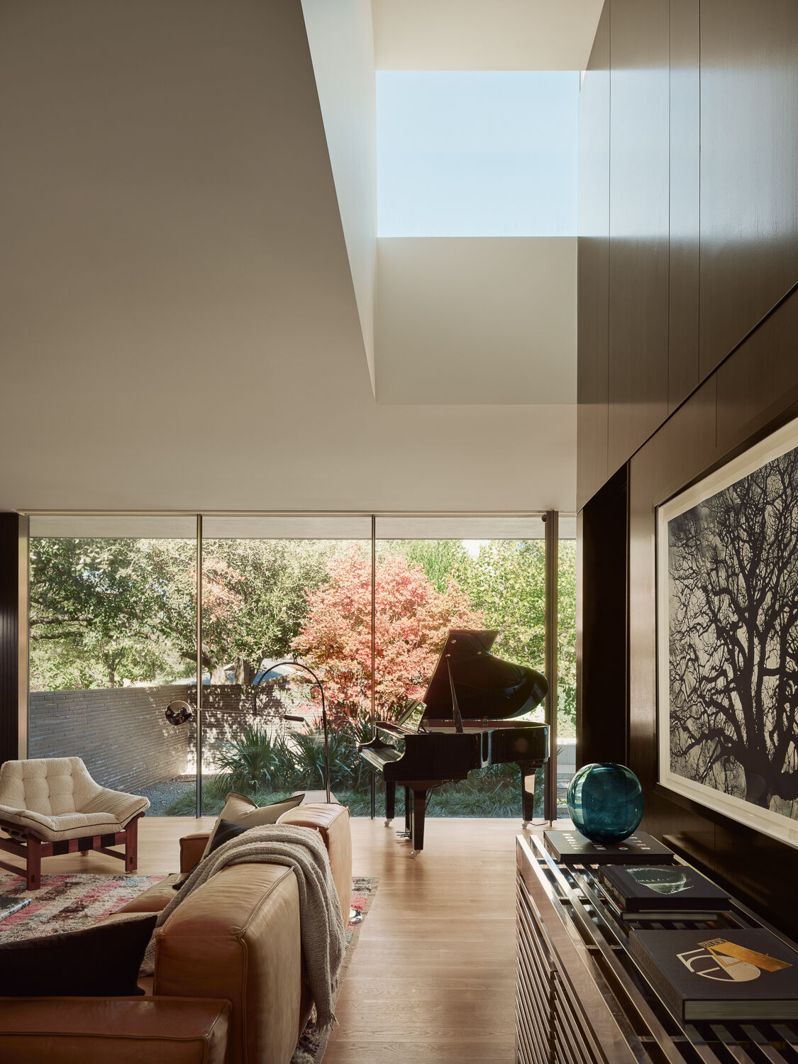 Explore a light-filled living room centered around courtyard views, floor-to-ceiling glazing, and a dramatic overhead monitor that draws natural light deep into the heart of the home.