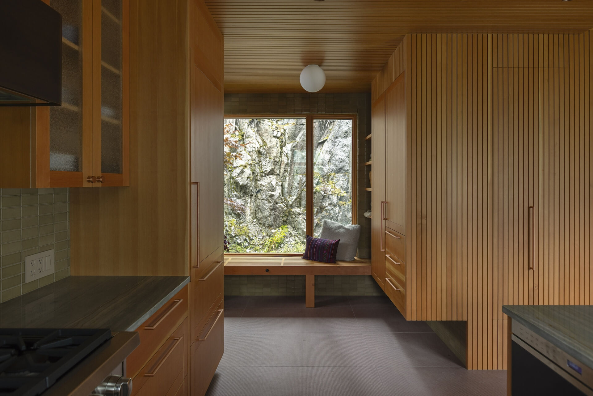 Douglas fir walls and ceilings pair with moss garden views in this warm and beautifully detailed mudroom design.