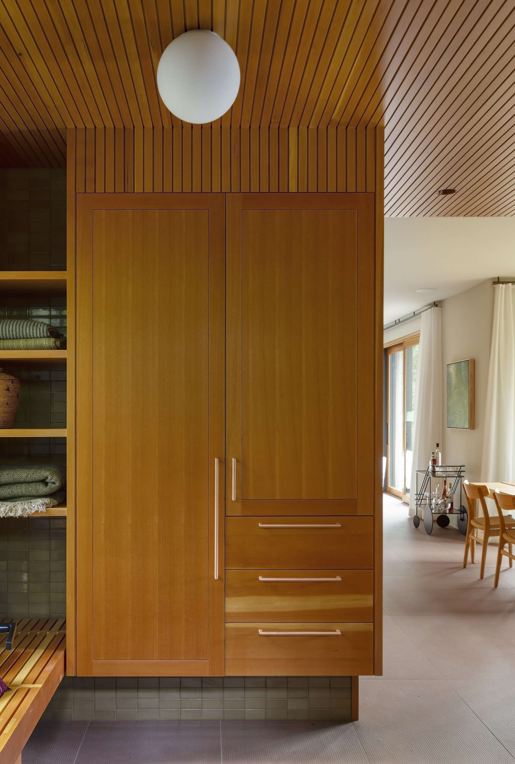 Douglas fir walls and ceilings pair with moss garden views in this warm and beautifully detailed mudroom design.