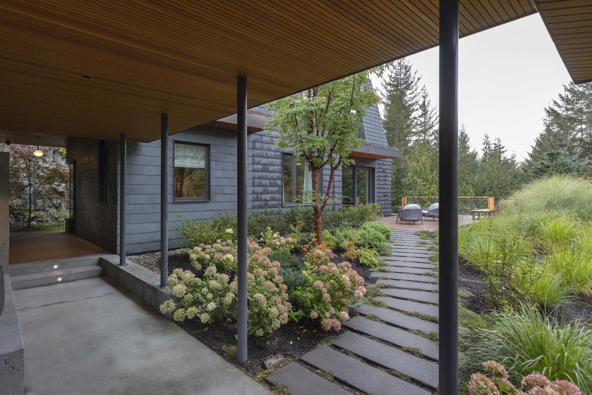 Covered pathways, mountain views, and green roofs create a dramatic entrance experience at this forest home in Whistler.