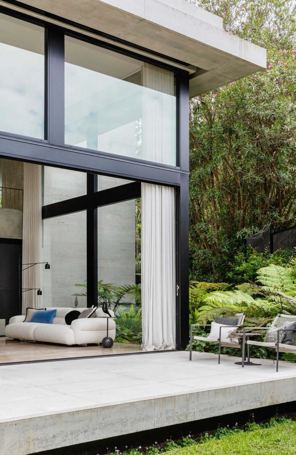 This modern Sydney home by Manolev Architects was designed around towering Bangalow palms, with a curved garden path and floating concrete deck creating a dramatic first impression.