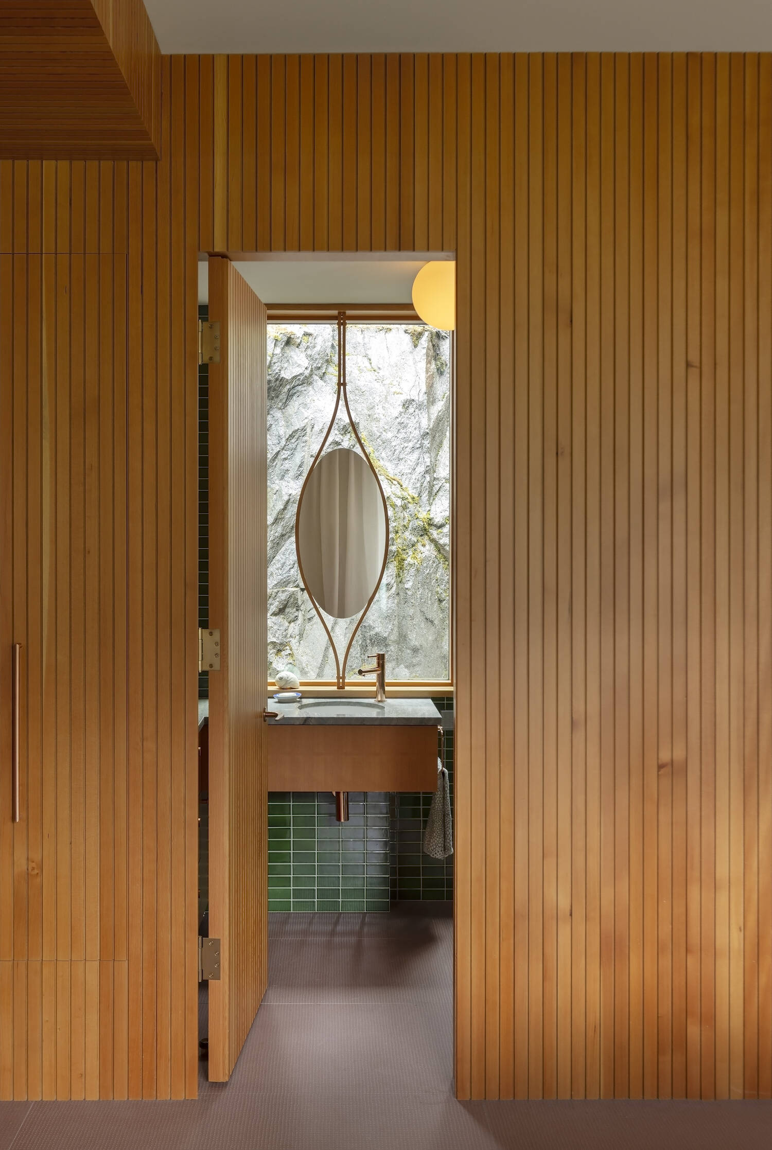 Green tiles, a curved Douglas fir mirror frame, and rock views bring personality into this small but striking powder room.
