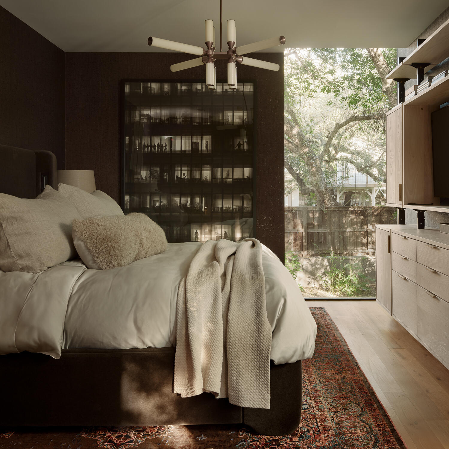 The primary bedroom combines rich wood finishes, custom built-ins, and expansive views of mature trees, creating a warm and sophisticated space filled with natural light.