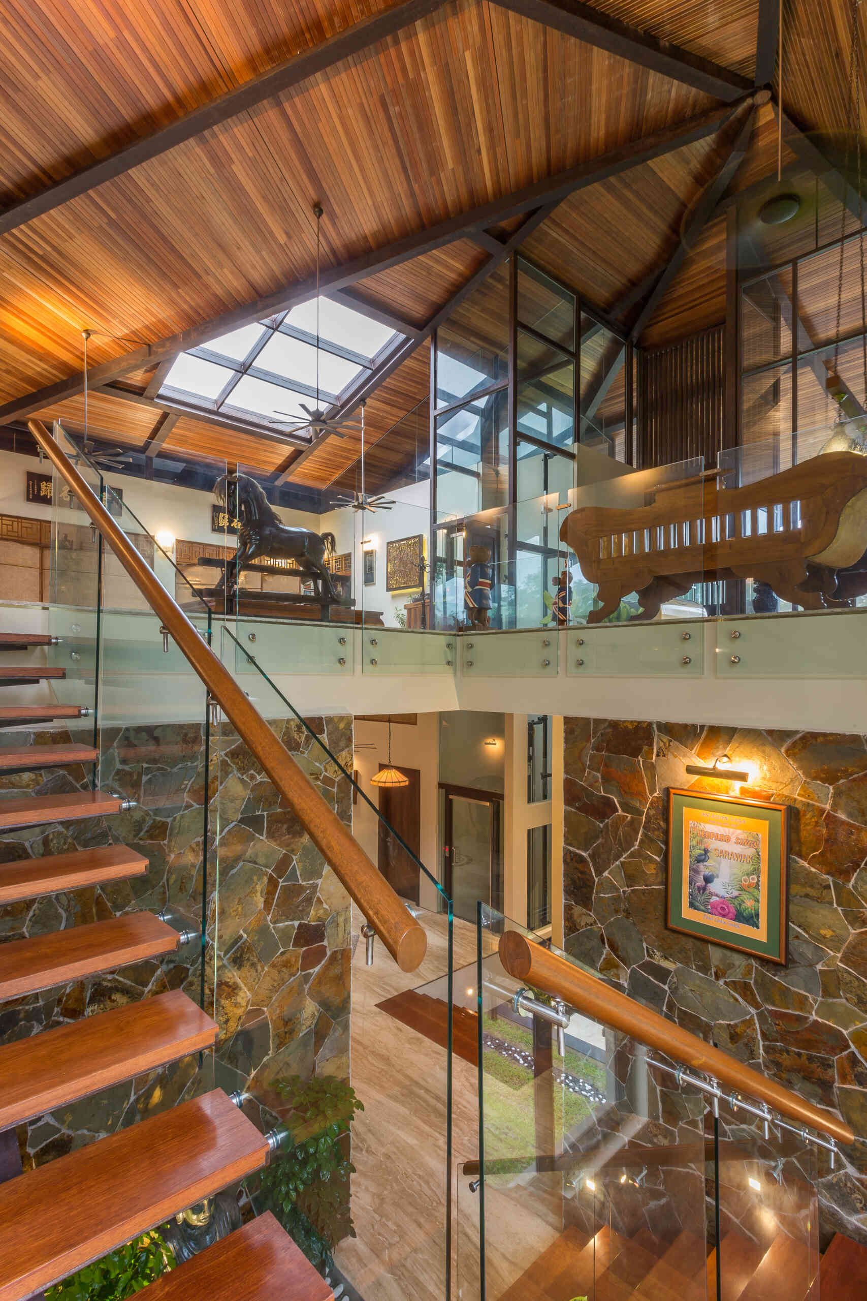 A sculptural staircase connects the cascading levels of Falanchity House, with jungle views, natural light and a timber canopy following the journey downward.