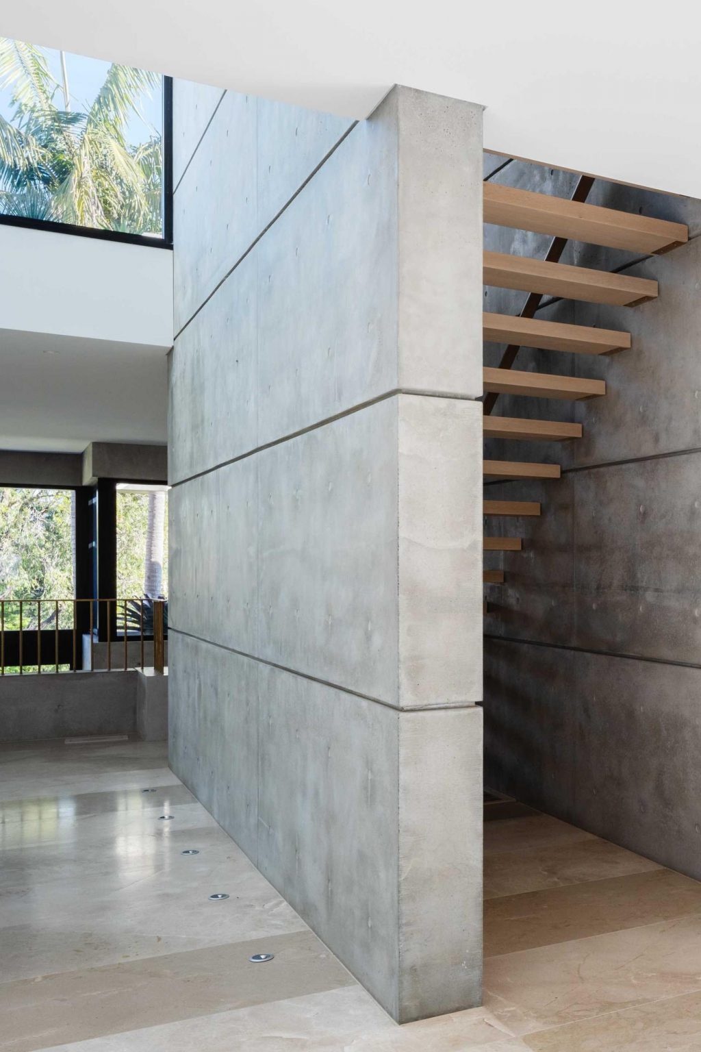 Concrete and timber staircases connect the multiple levels of this modern Sydney home, adding warmth and sculptural detail to the minimalist interior.