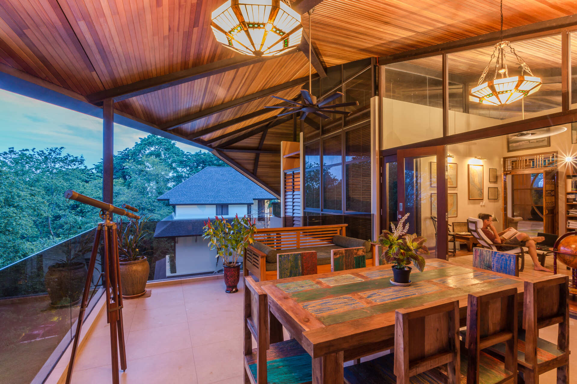 The study and terrace areas take advantage of the home’s elevated position within Ukay Heights. Openings toward the landscape bring in cooler breezes while framing views across the vegetation surrounding the site.

The terrace extends the interior outward beneath the long roof overhangs, creating shaded outdoor areas protected from the tropical climate.