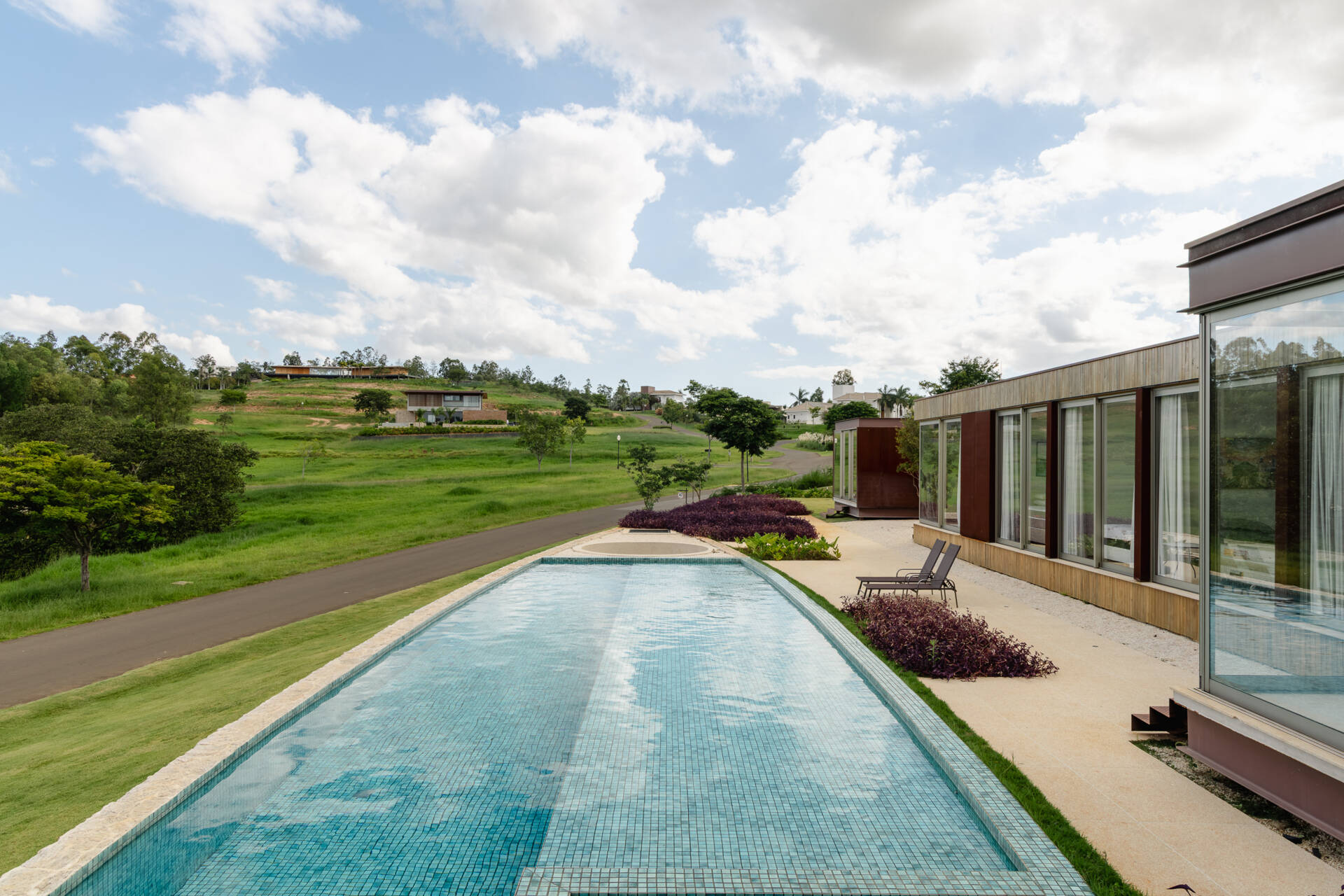 Built into a raised stone platform, the swimming pool terrace at Casa Themis combines panoramic countryside views with modern outdoor living and warm natural materials.