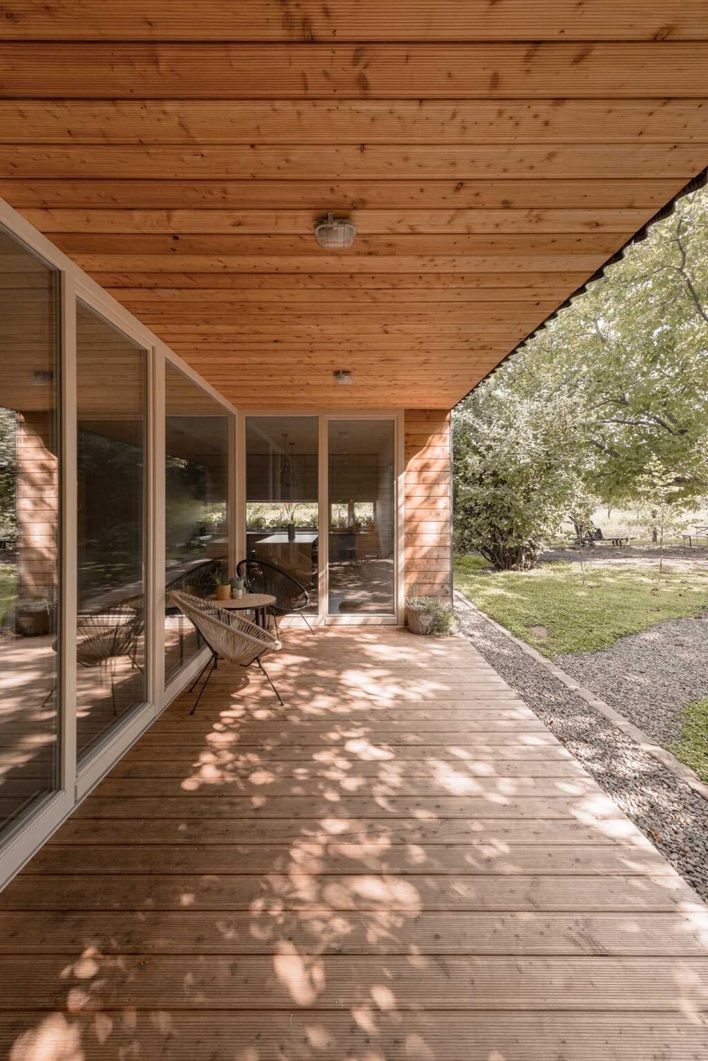Larch wood-lined alcoves add warmth to this black modern home, creating inviting outdoor spaces that open directly toward the walnut grove.