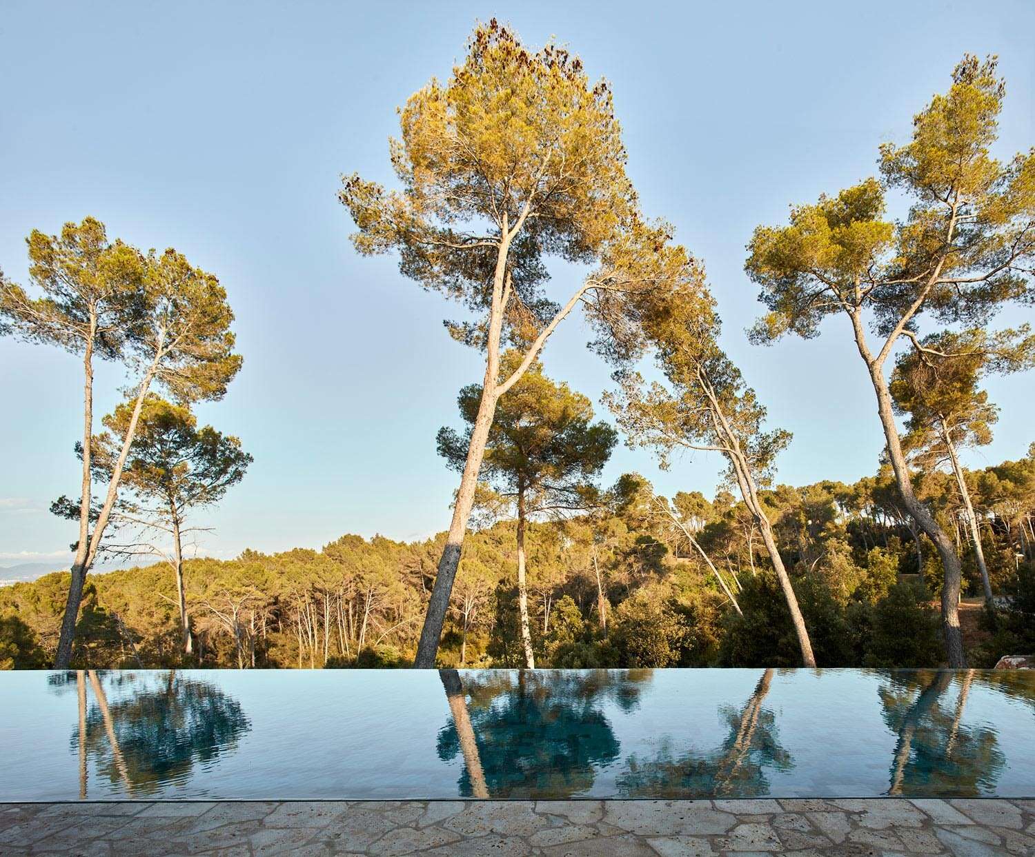 Off-white concrete, wood, and weathering steel help this modern Spanish home blend beautifully into the surrounding forest landscape.