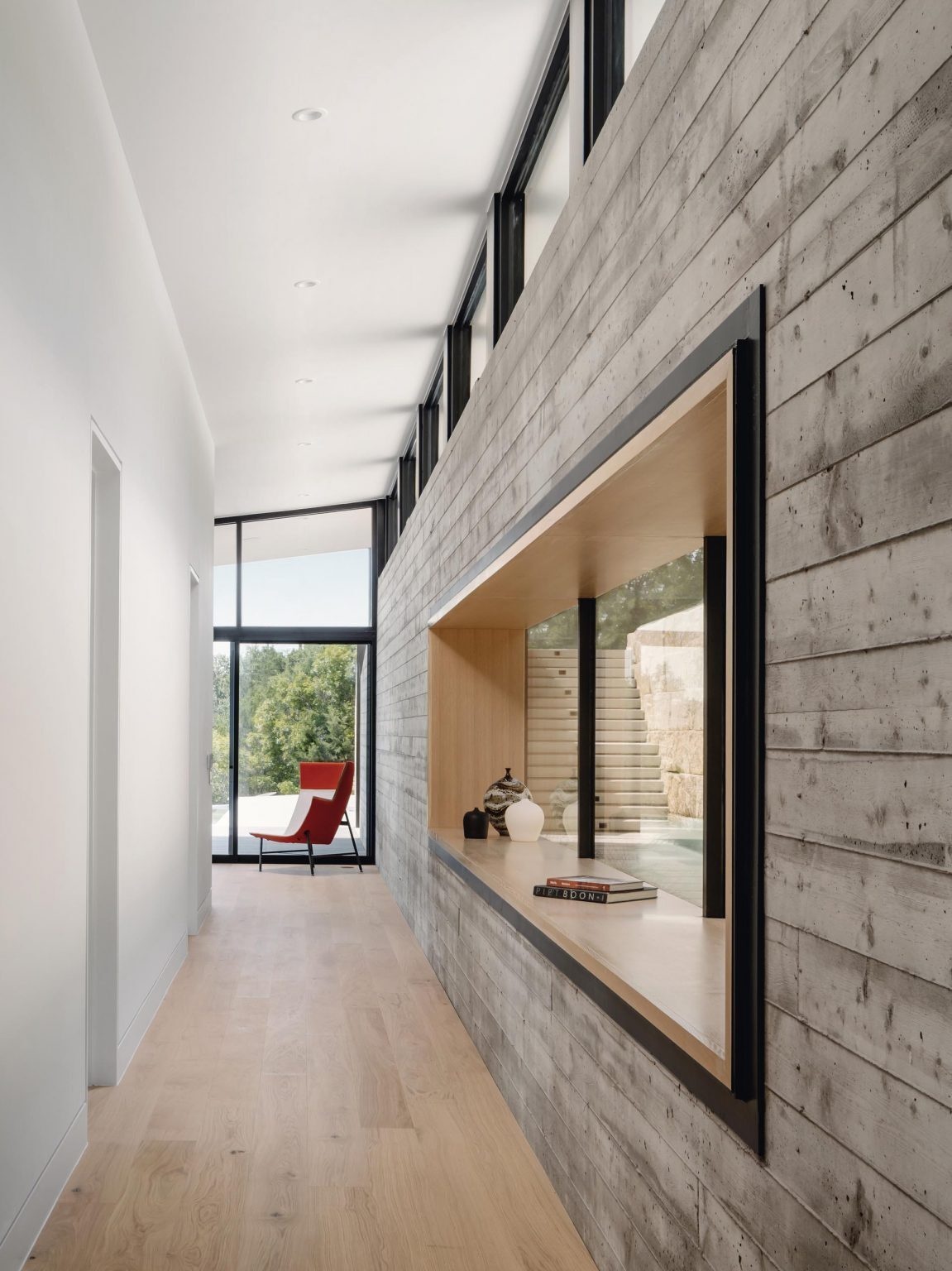 A hallway lined with board-formed concrete connects the two living spaces while also leading to the bedrooms, bathrooms, and guest areas located in the southern wing of the house.