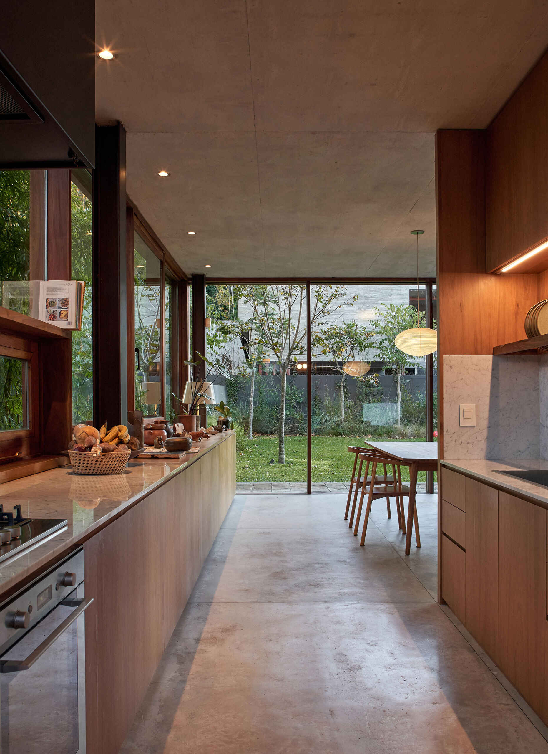 A sleek kitchen lines the wall, with cabinetry and counters extending into the dining area for a clean, continuous look.